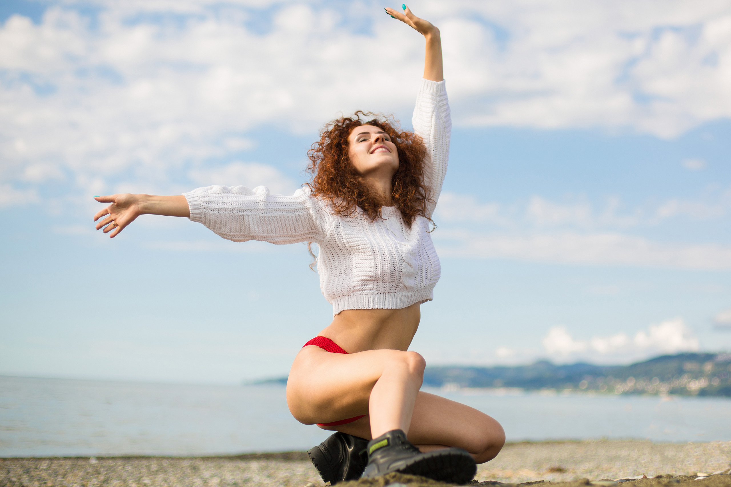 девушка сидит на корточках на фоне моря