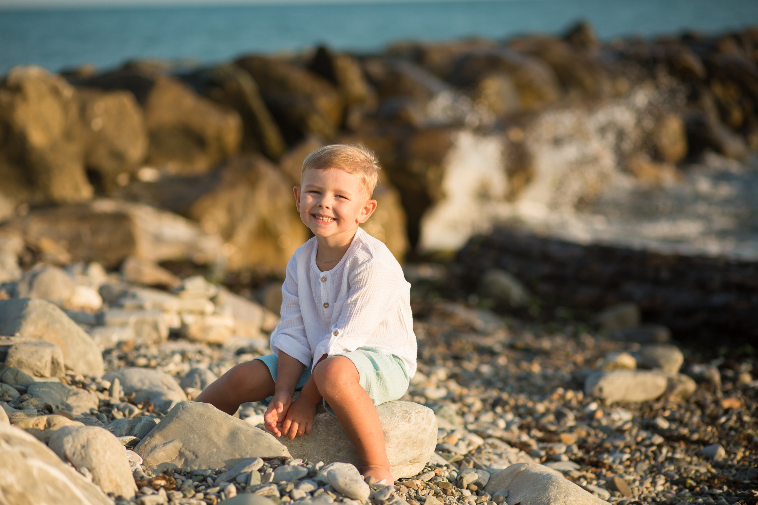 маленький мальчик сидит довольный у моря