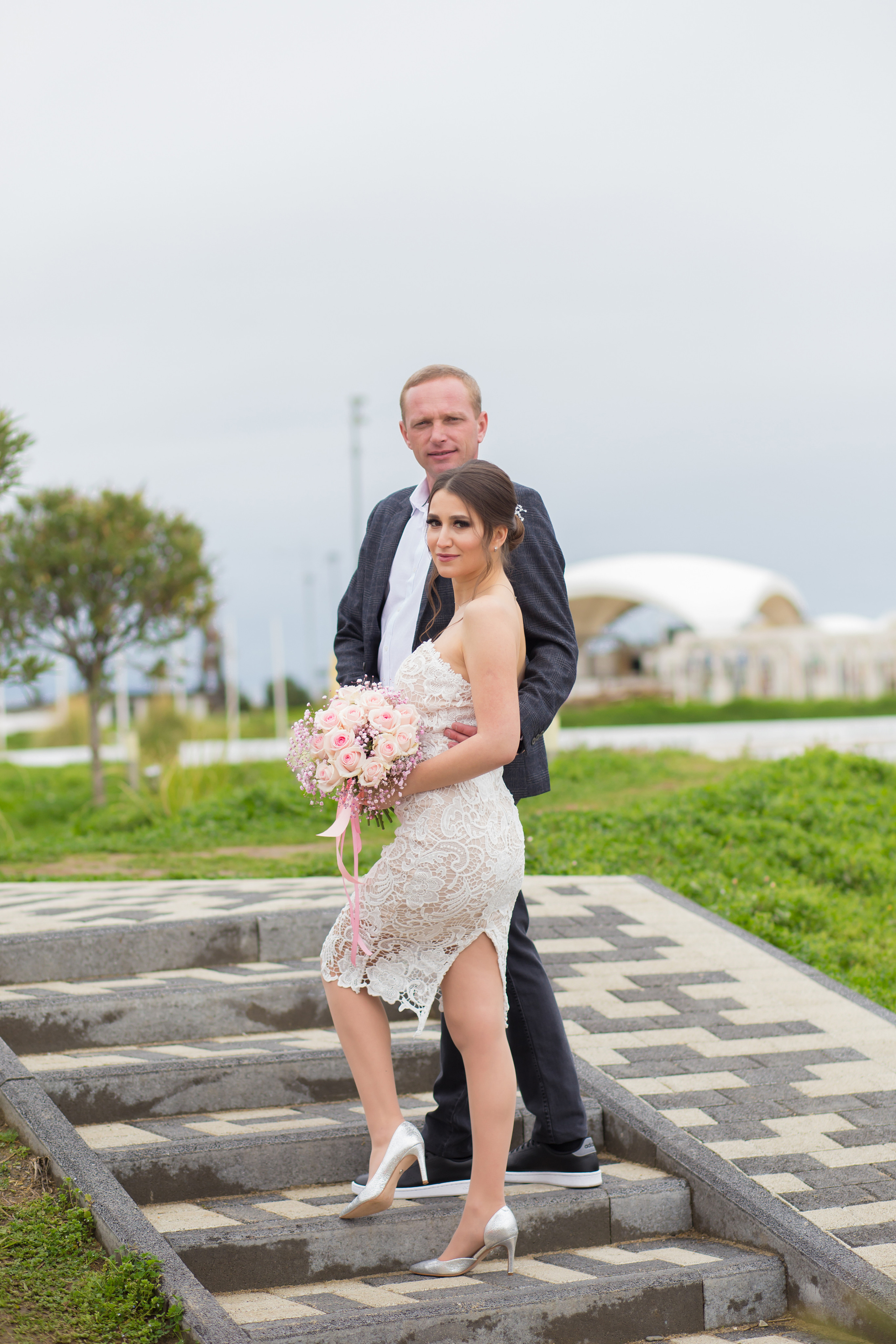 невеста с букетом и жених стоят на ступеньках