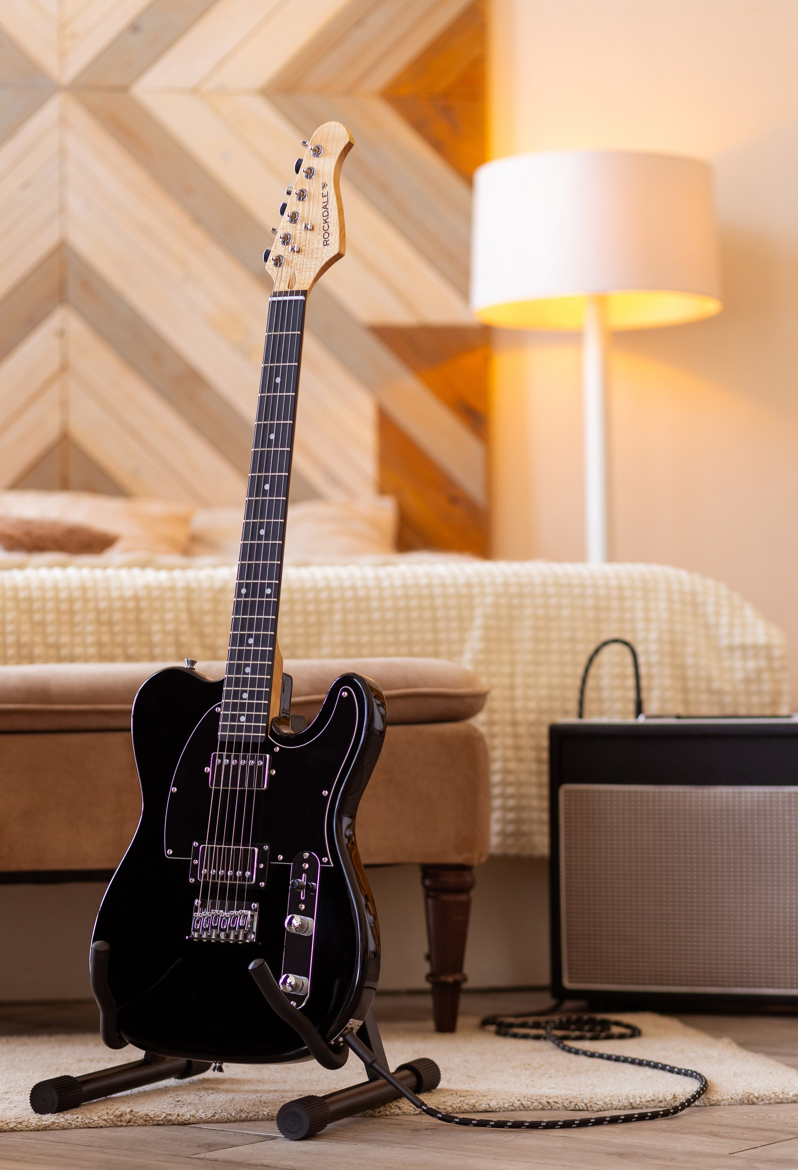 На фоне освященного бра деревянного панно на подставке стоит акустическая гитара.