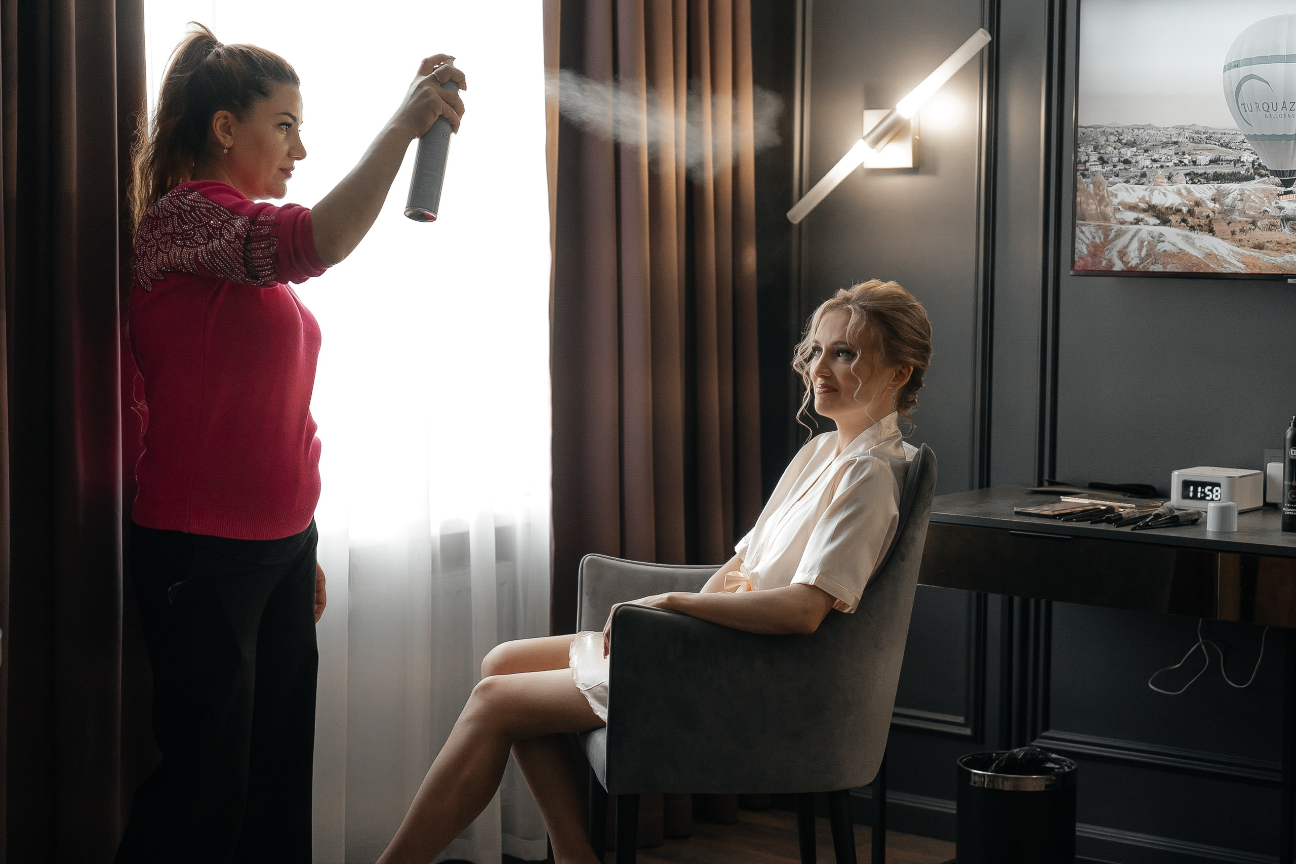 Сборы невесты в отеле аквалина. Визажист прыскает лаком на волосы