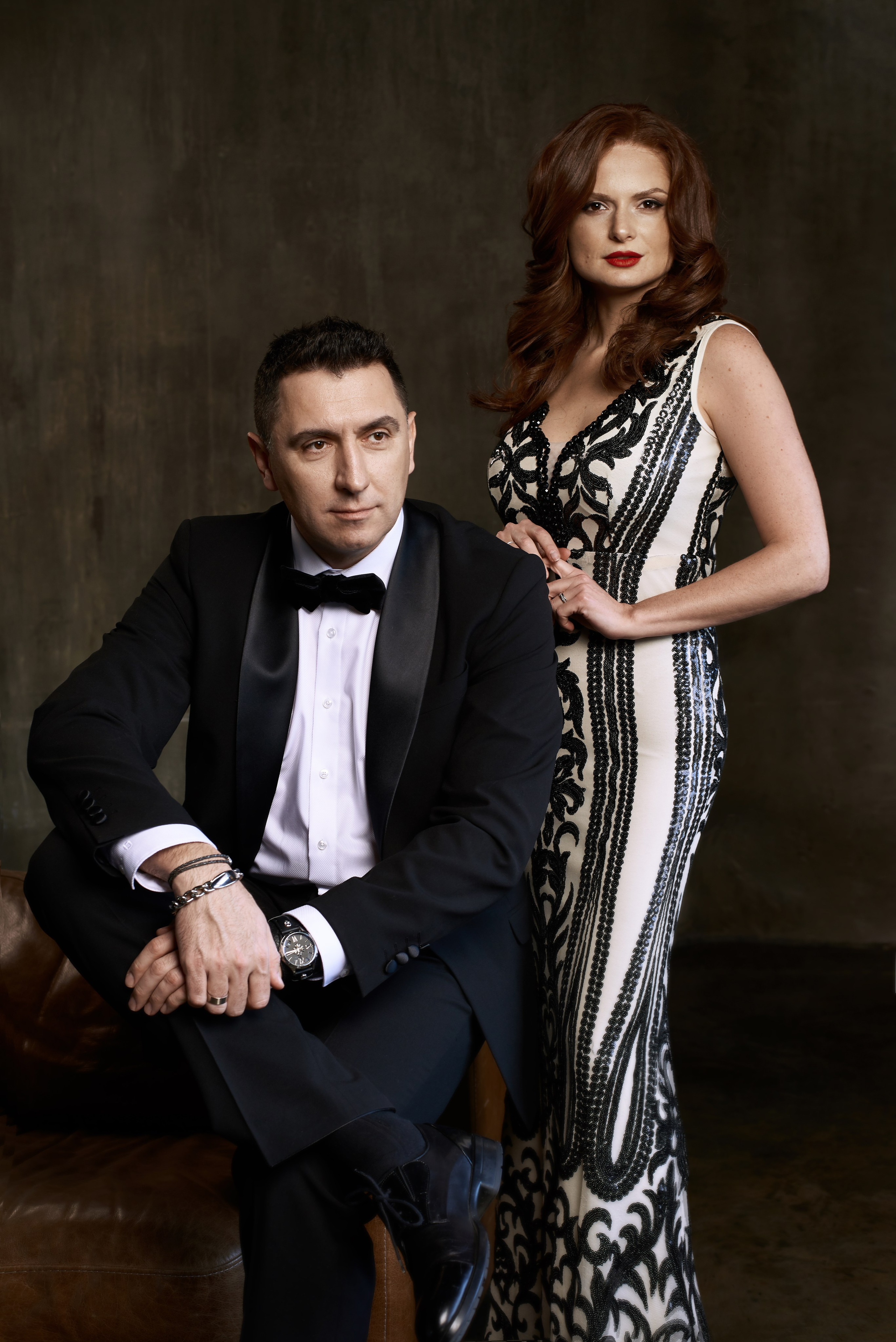 Фотосессия мужчины и женщины в студии с темным фоном в вечерних образах