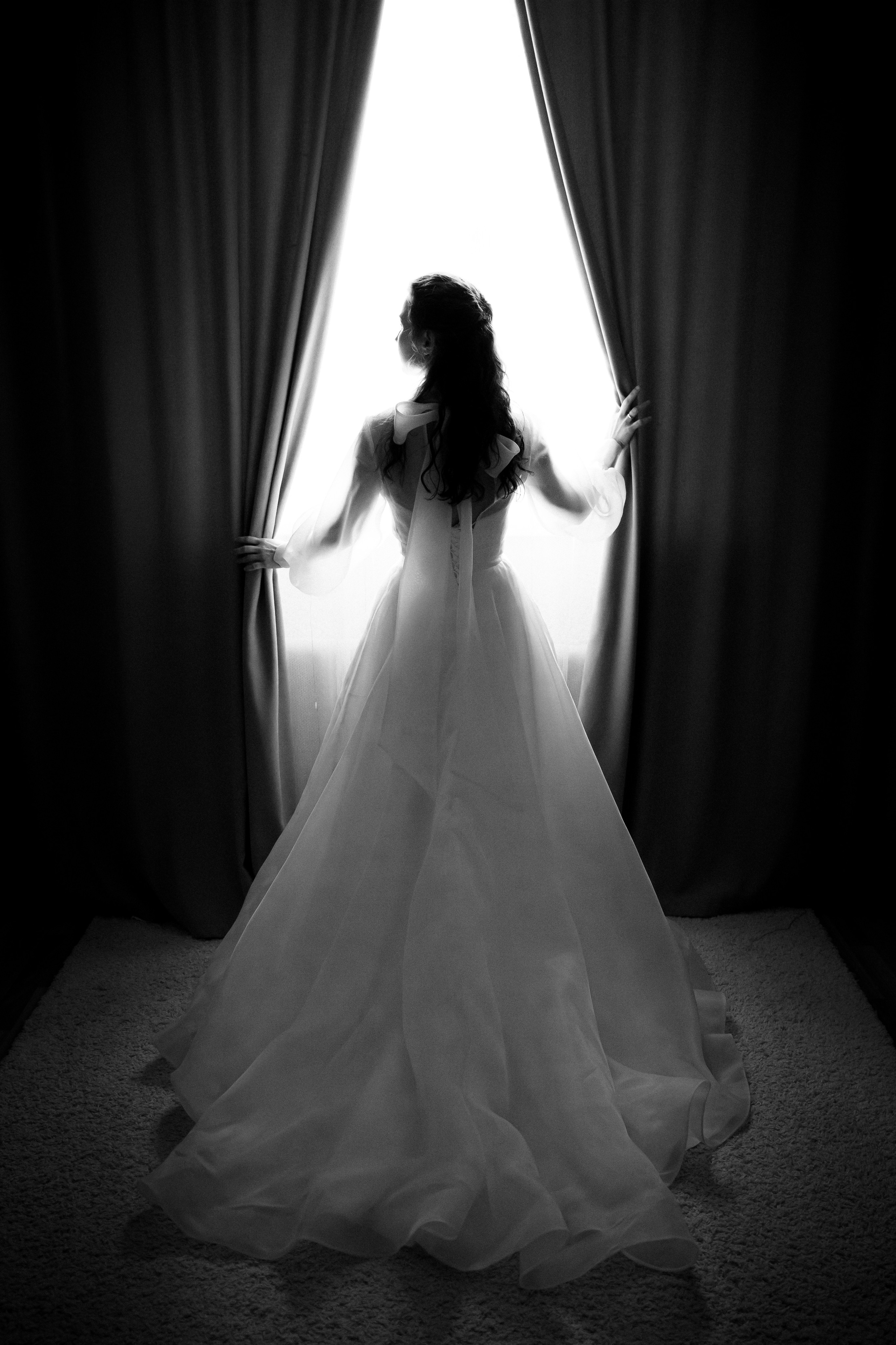 молодая невеста стоит на фоне окна