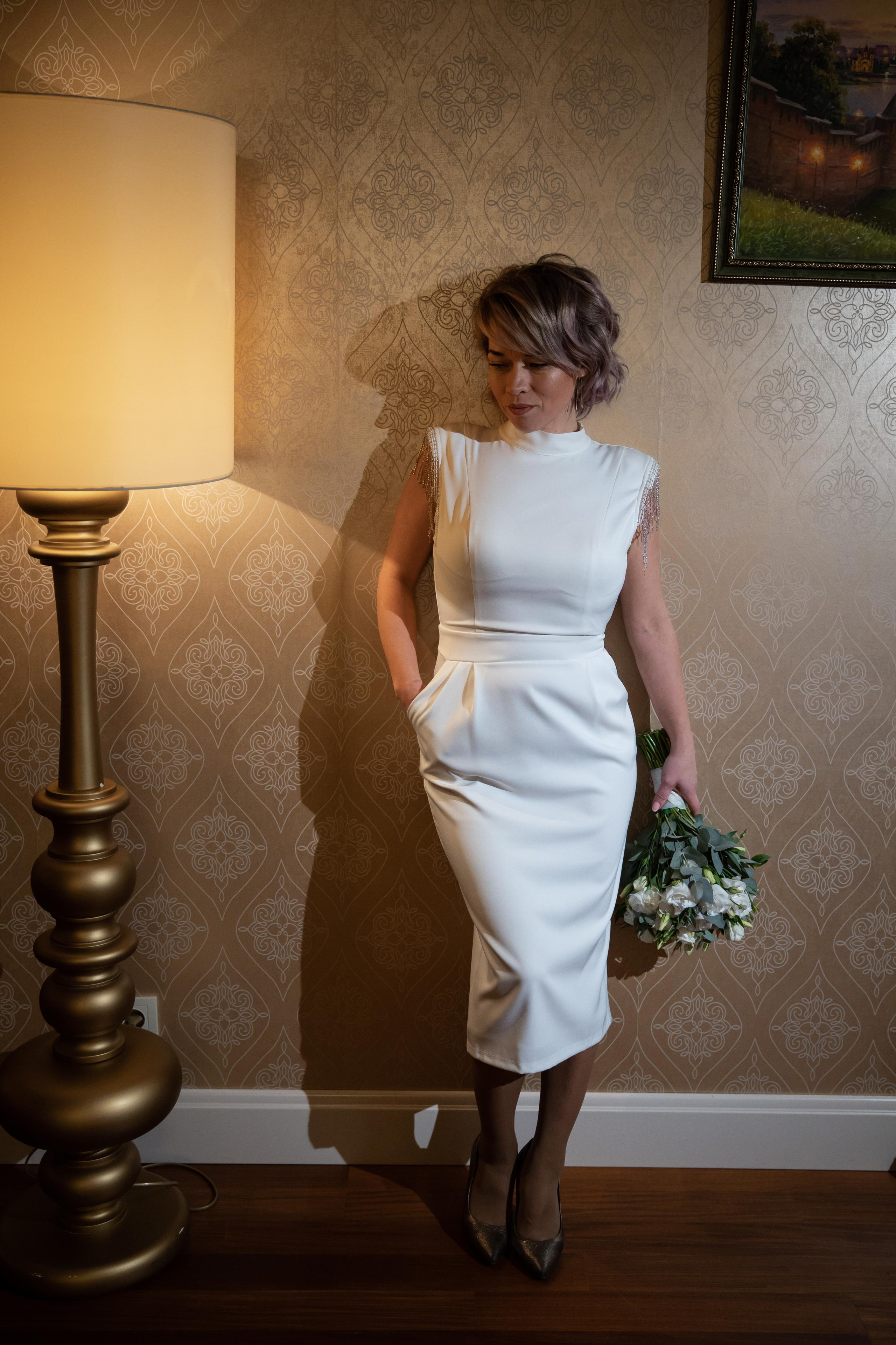 невеста с букетом цветов стоит у стены