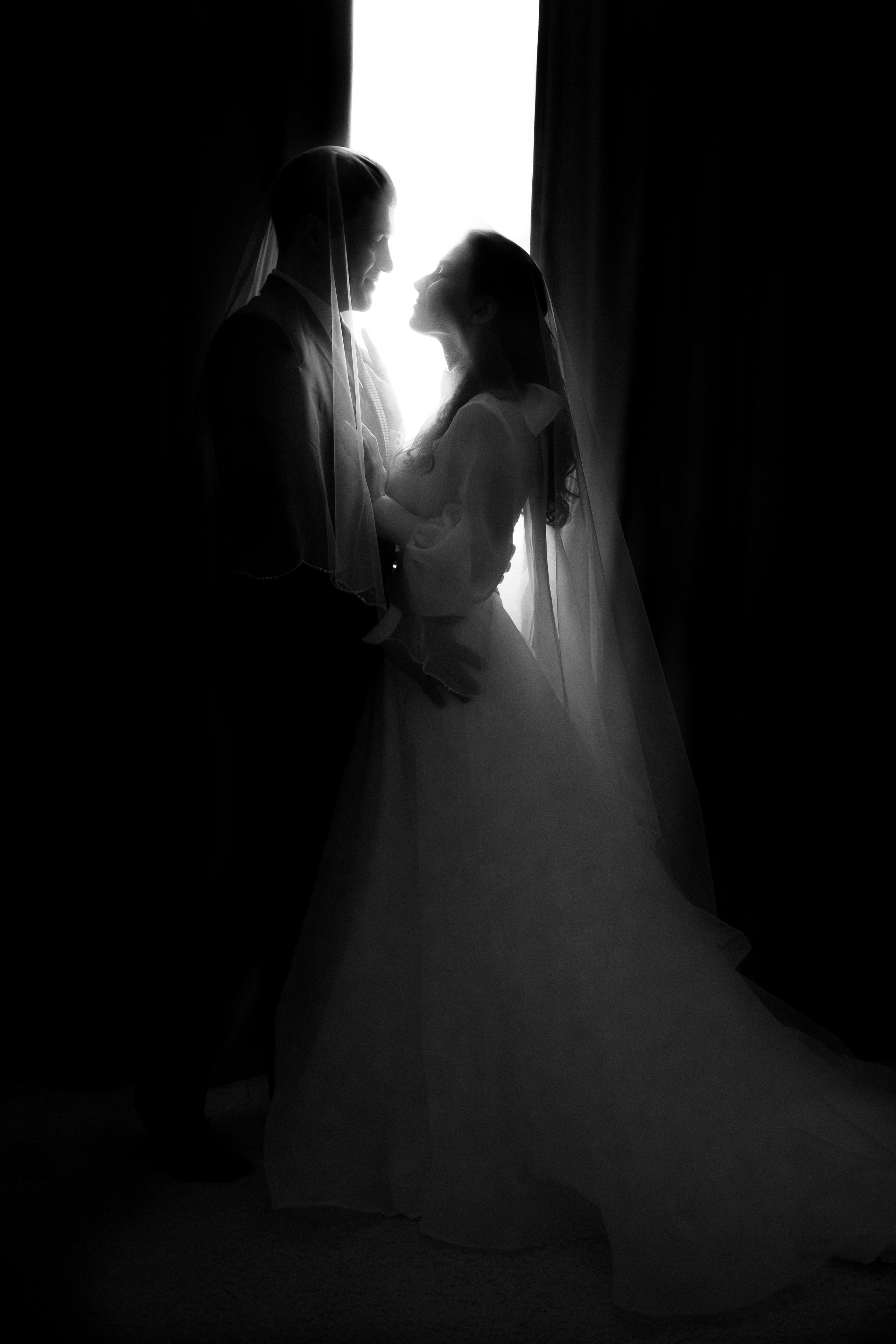 жених и невеста стоят на фоне окна