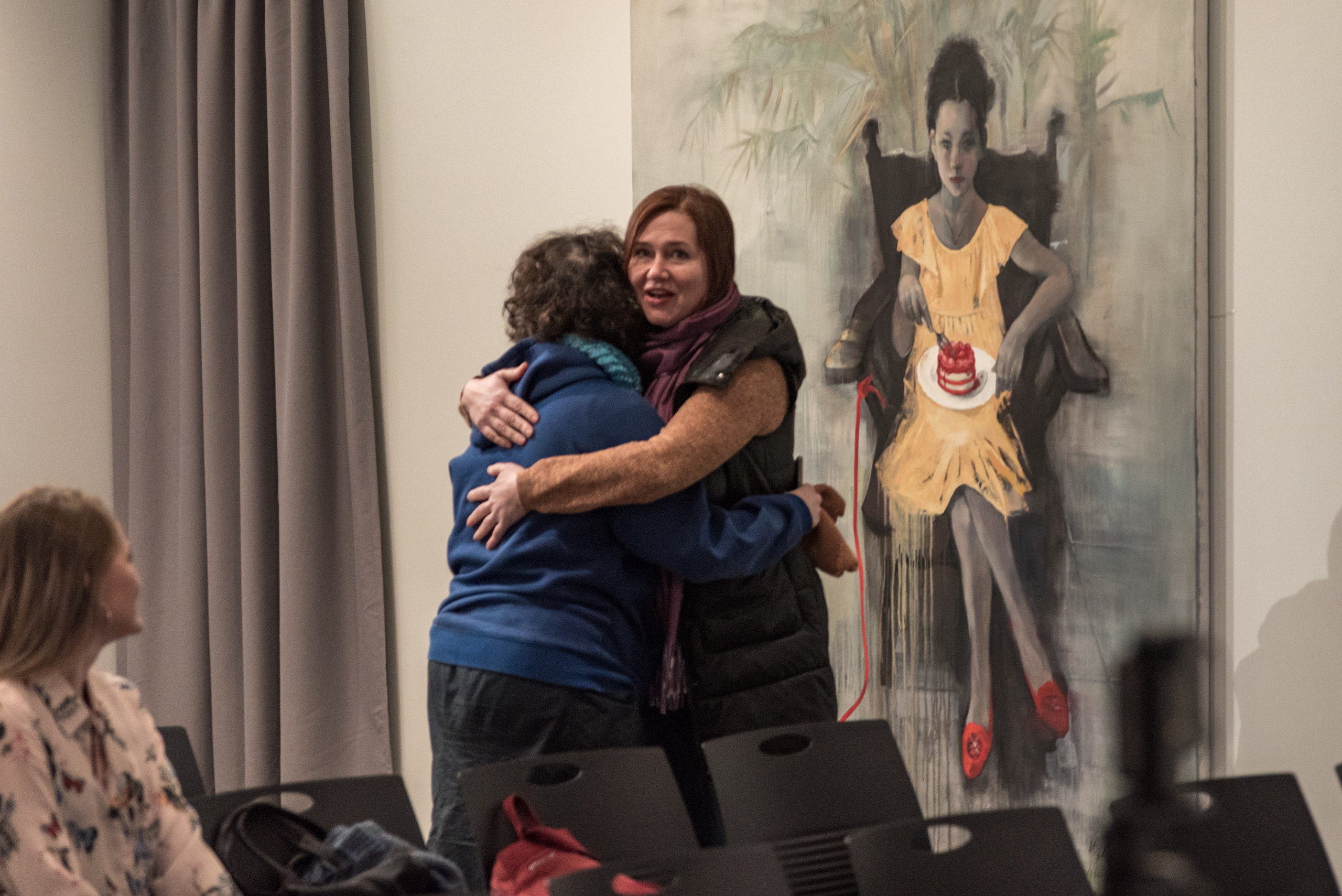 Две знакомые женщины встретились на семинаре. Обнимают друг друга.