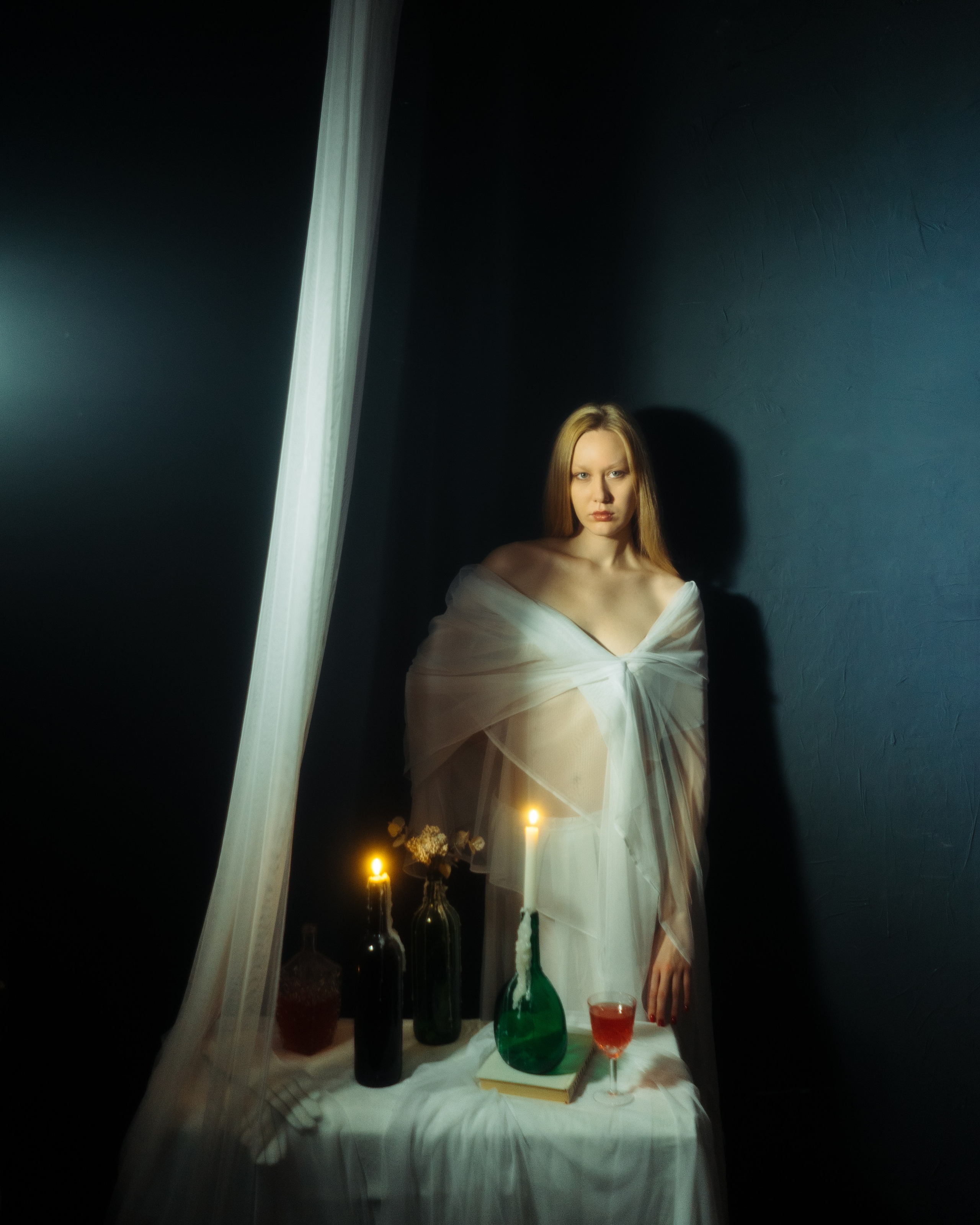 Авторская женская фотосессия в студии, девушка стоит у стола со свечами, атмосферный портрет в темной художественной стилистике