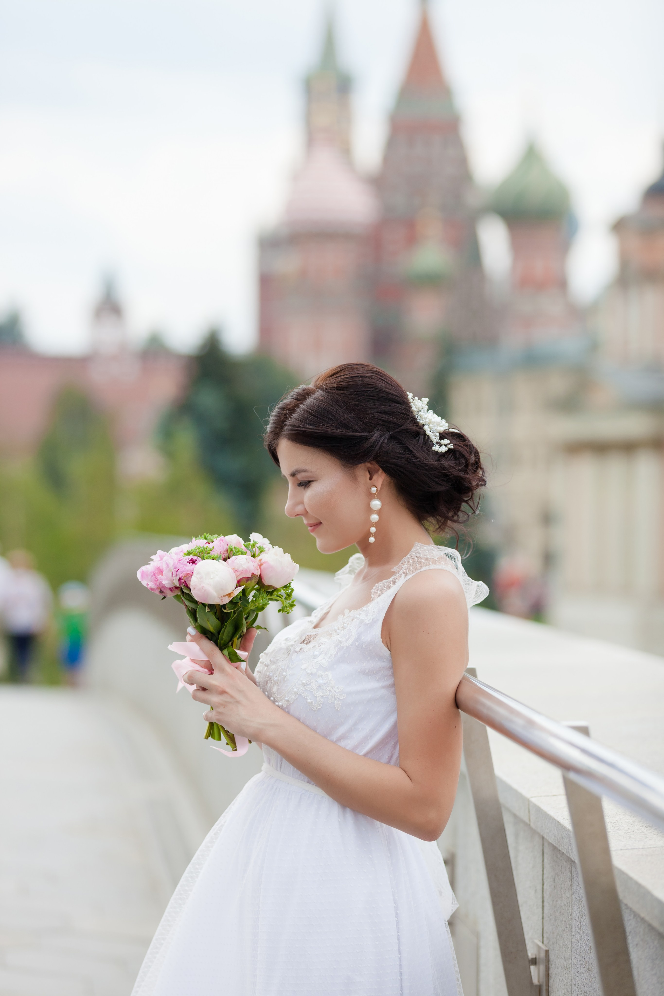 Невеста стоит с красивым розовым букетом цветов на фоне Кремля