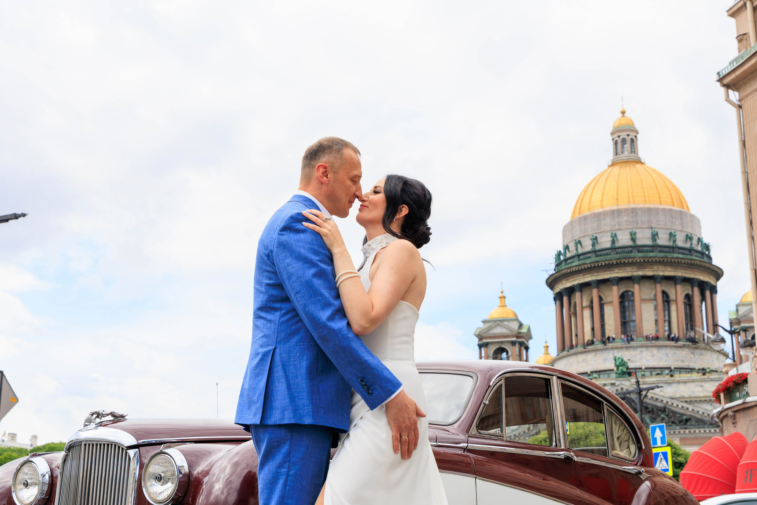 Жених и невеста целуются на фоне Исаакиевского собора в Санкт-Петербурге.