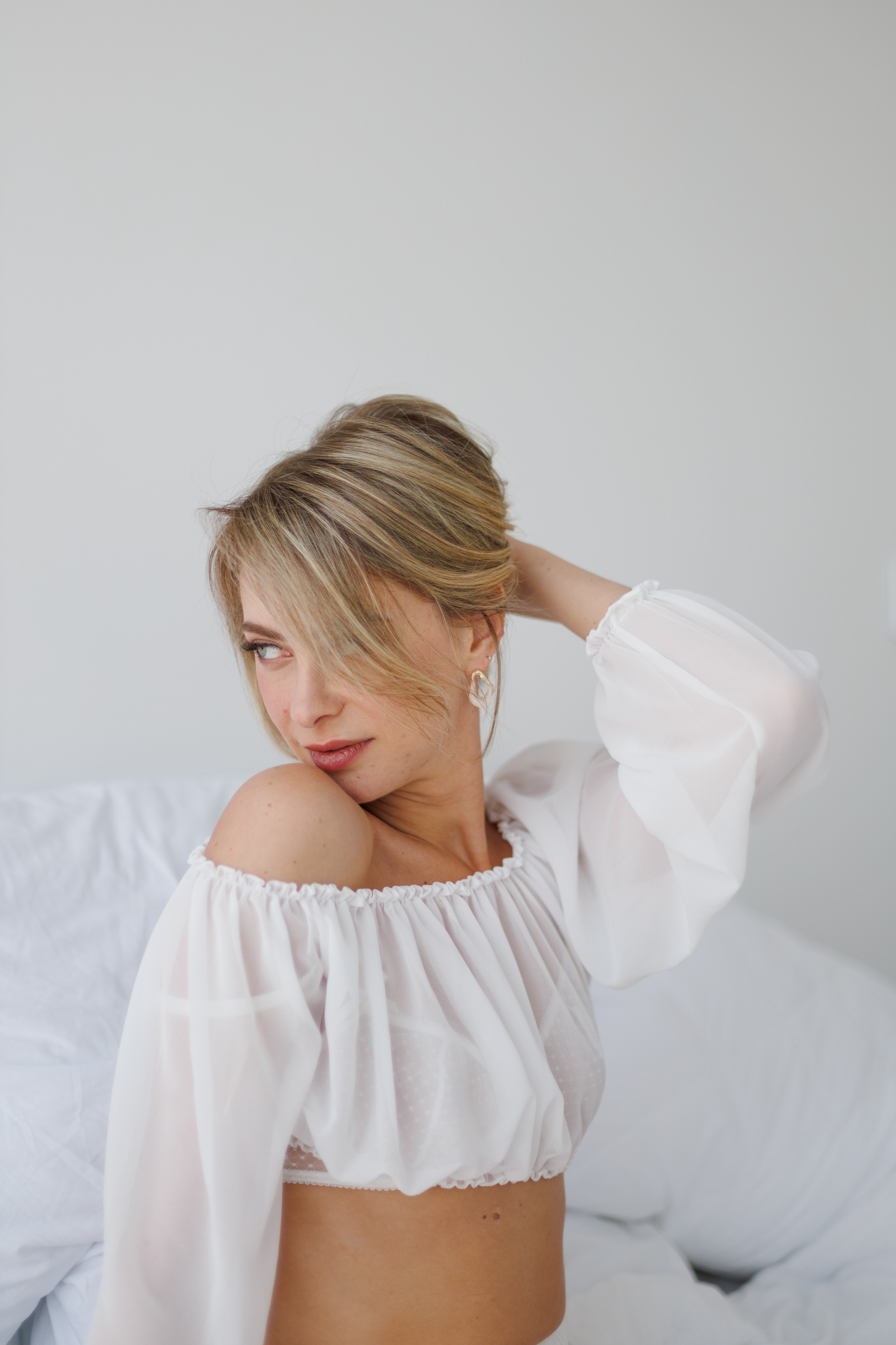 Фотосессия девушки в белом платье, фотосессия в светлых тонах, фотография девушки в студии, девушка лежит на кровати