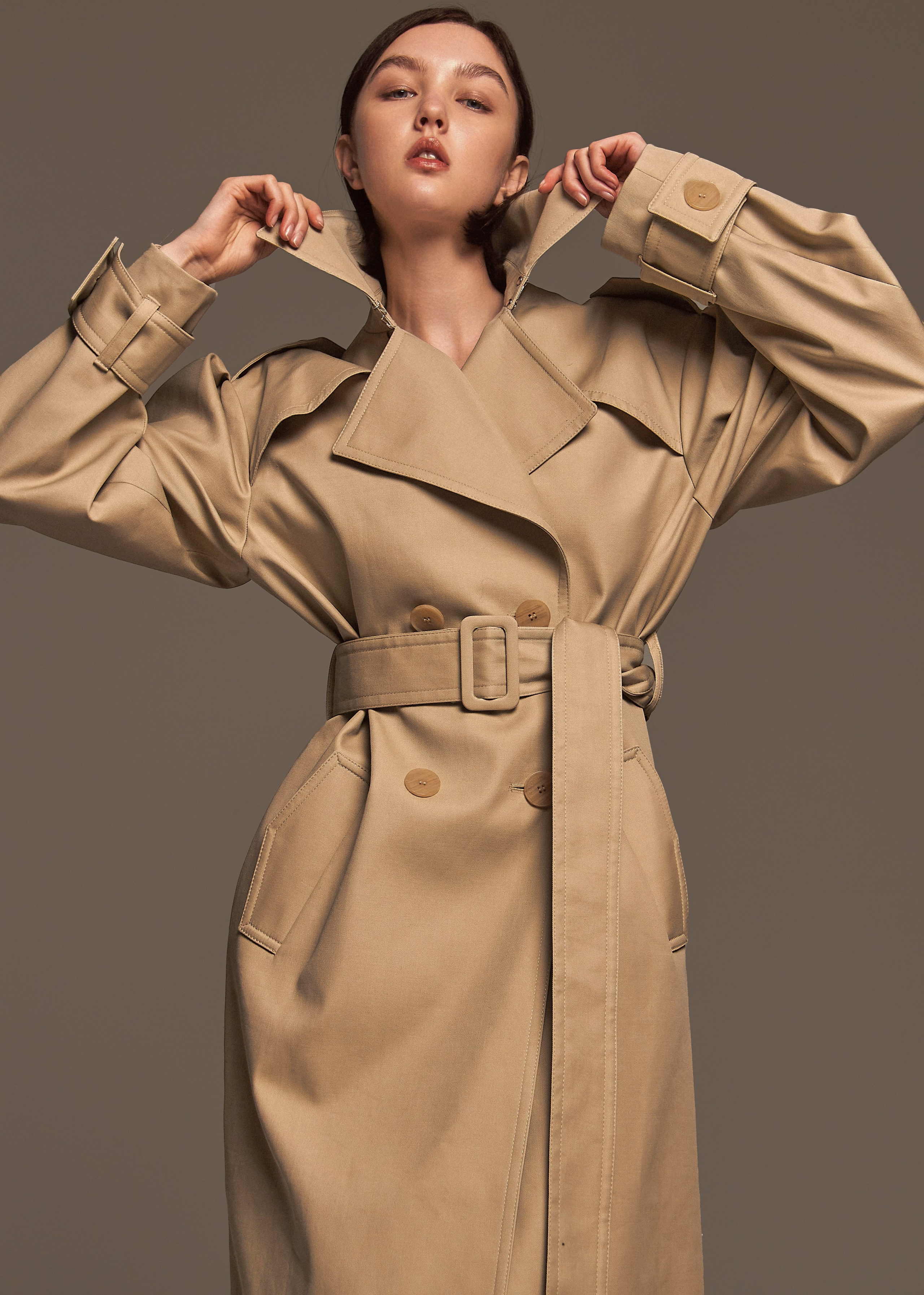Fashion photographer and model posing in a trench coat during a studio photoshoot. Dramatic lighting, high fashion, neutral background. Фотограф и модель в стиле фэшн в плаще в студии. Студийная съемка, драматичный свет, нейтральный фон.