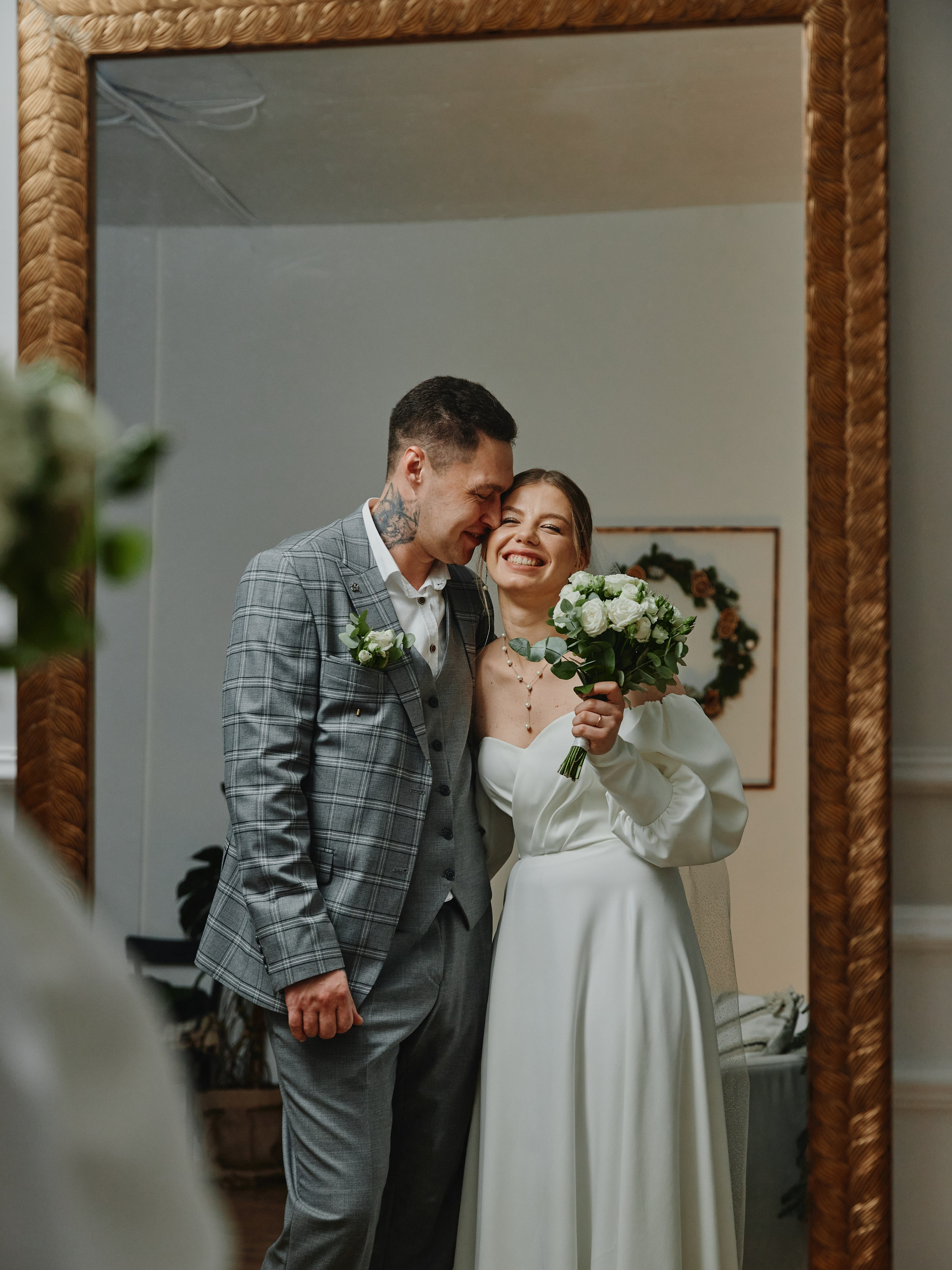 Жених и невеста улыбаются, смотрят в зеркало