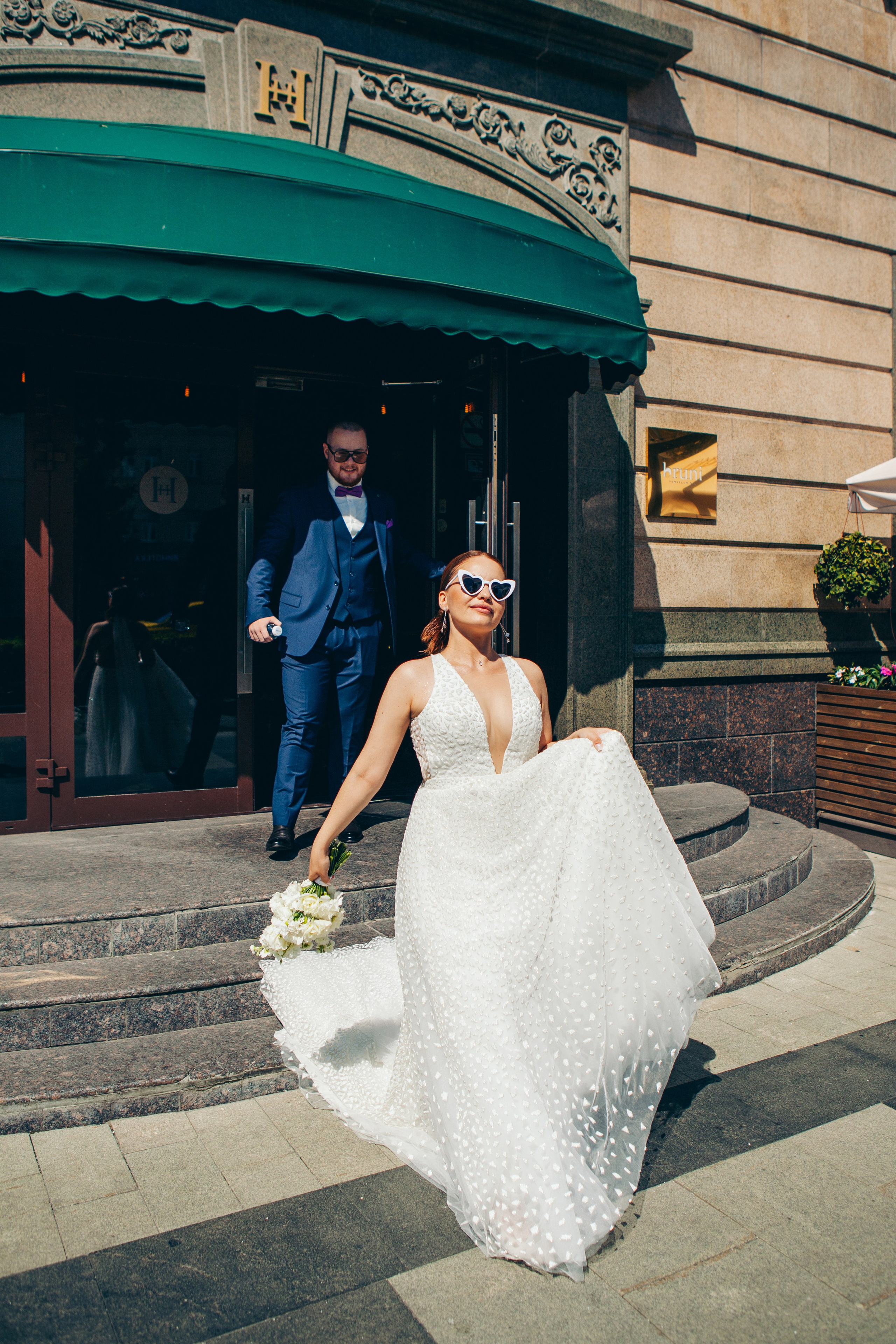 невеста и жених выходят из отеля гулять по парку