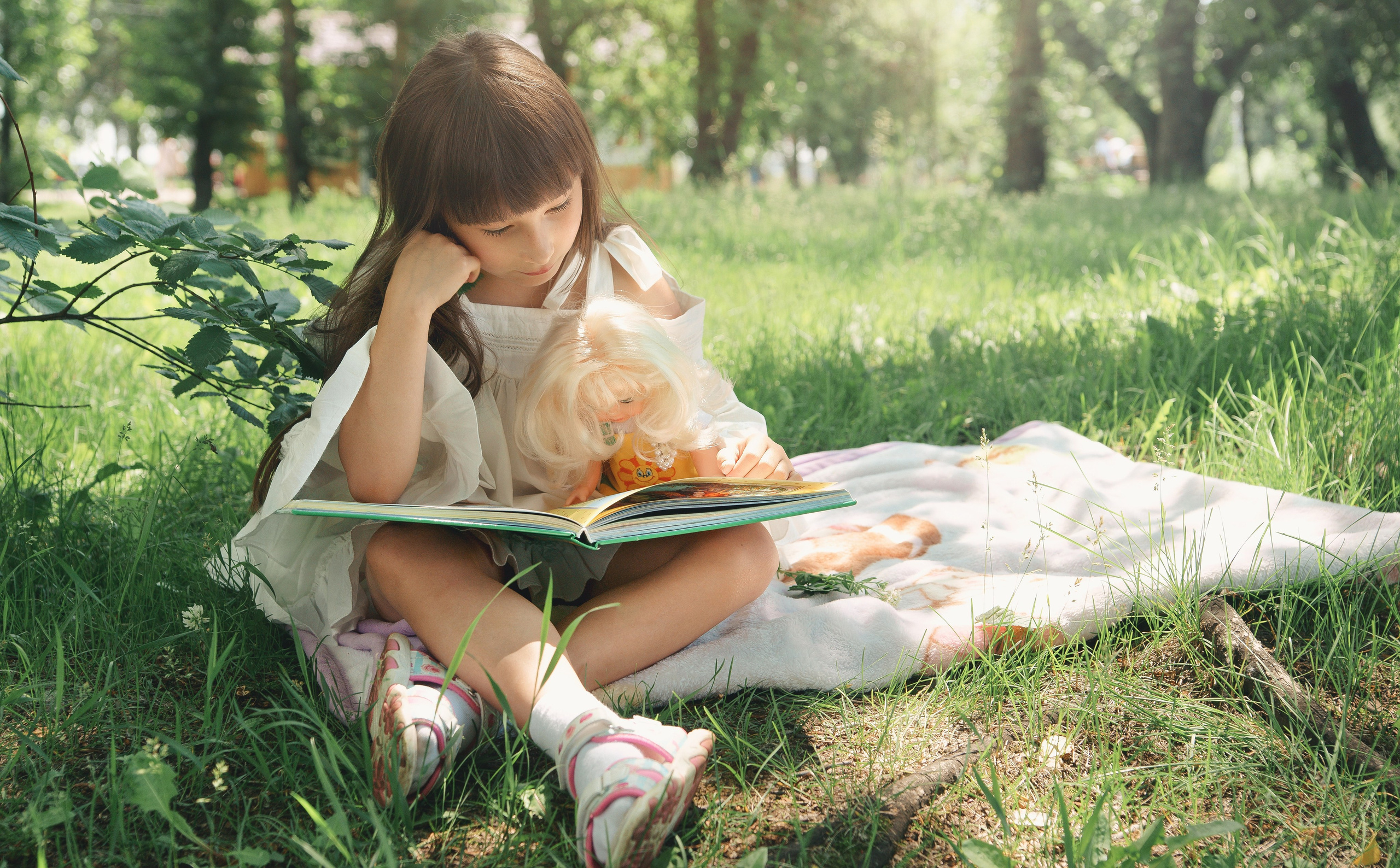 Детская фотосессия летом - девочка на траве читает книгу