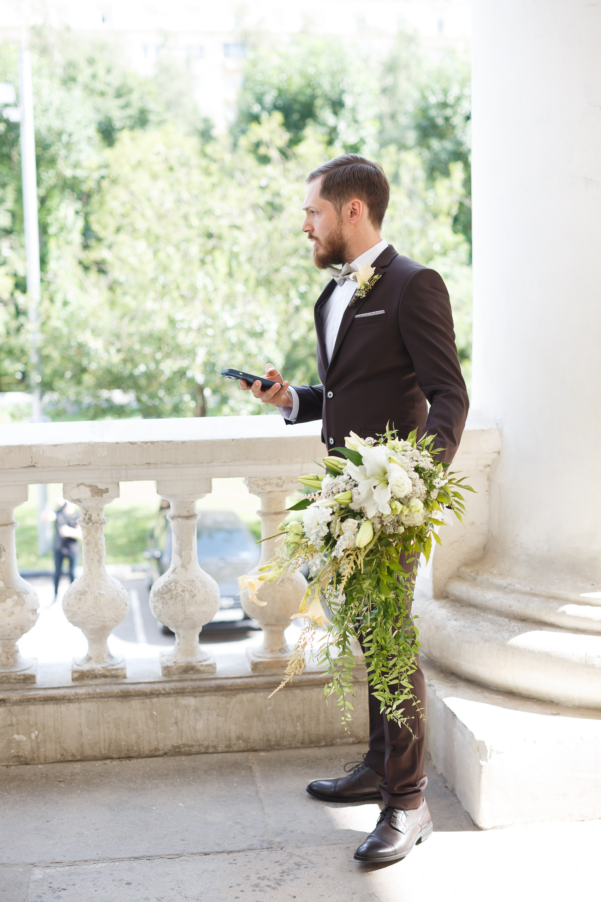 Венчание в храме святого благоверного царевича Димитрия при первой градской больнице г. Москвы. Жених держит в руке букет и стоит на улице.