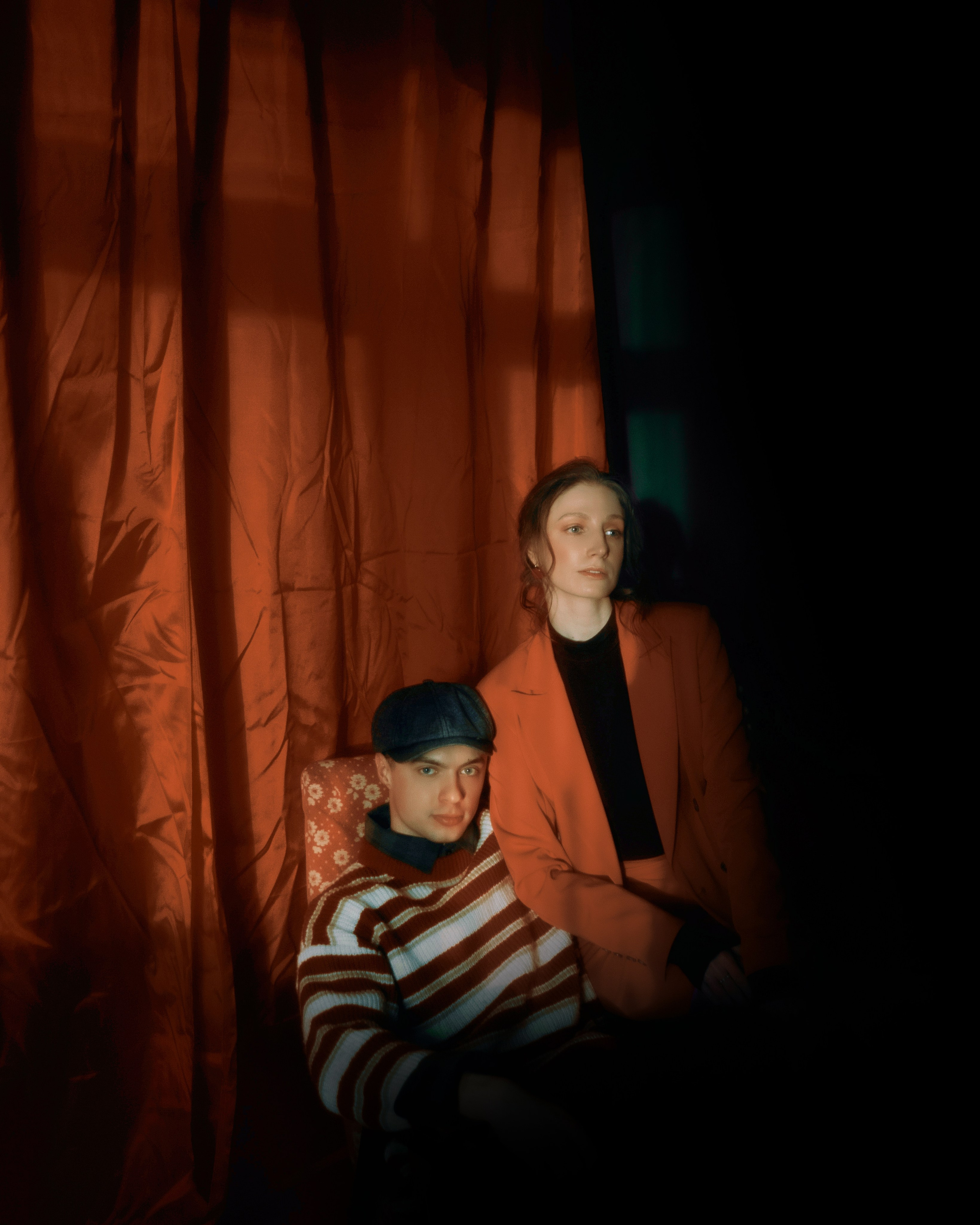 Авторская фотосессия пары в фотостудии Петербурга, художественный портрет с темным светом и красным фоном для атмосферной парной съемки