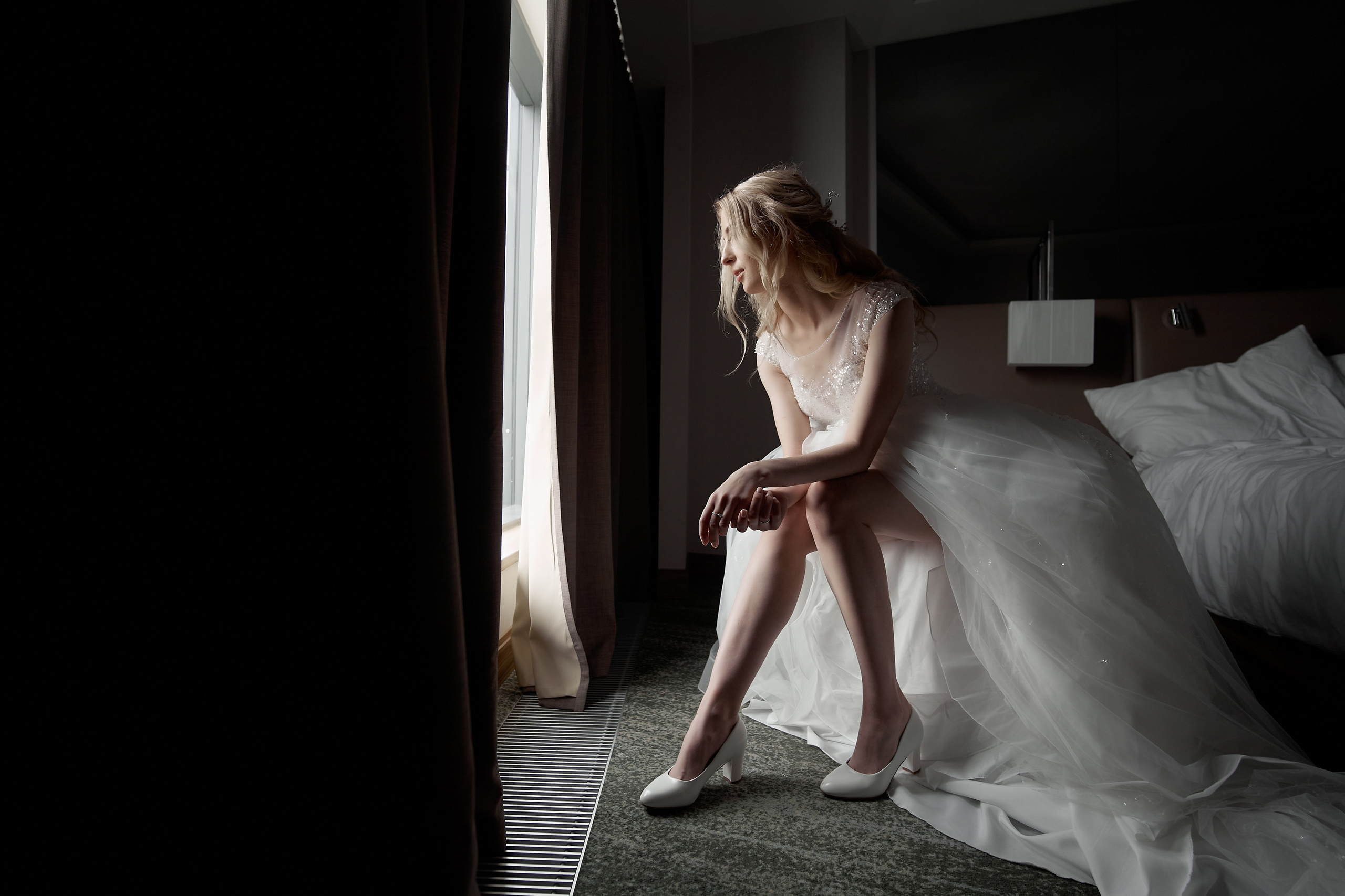 Невеста у окна одевает свадебные туфли Свадебная фотосъемка в Москве. Свадебный фотограф в Москве  Сергей Гаварос.