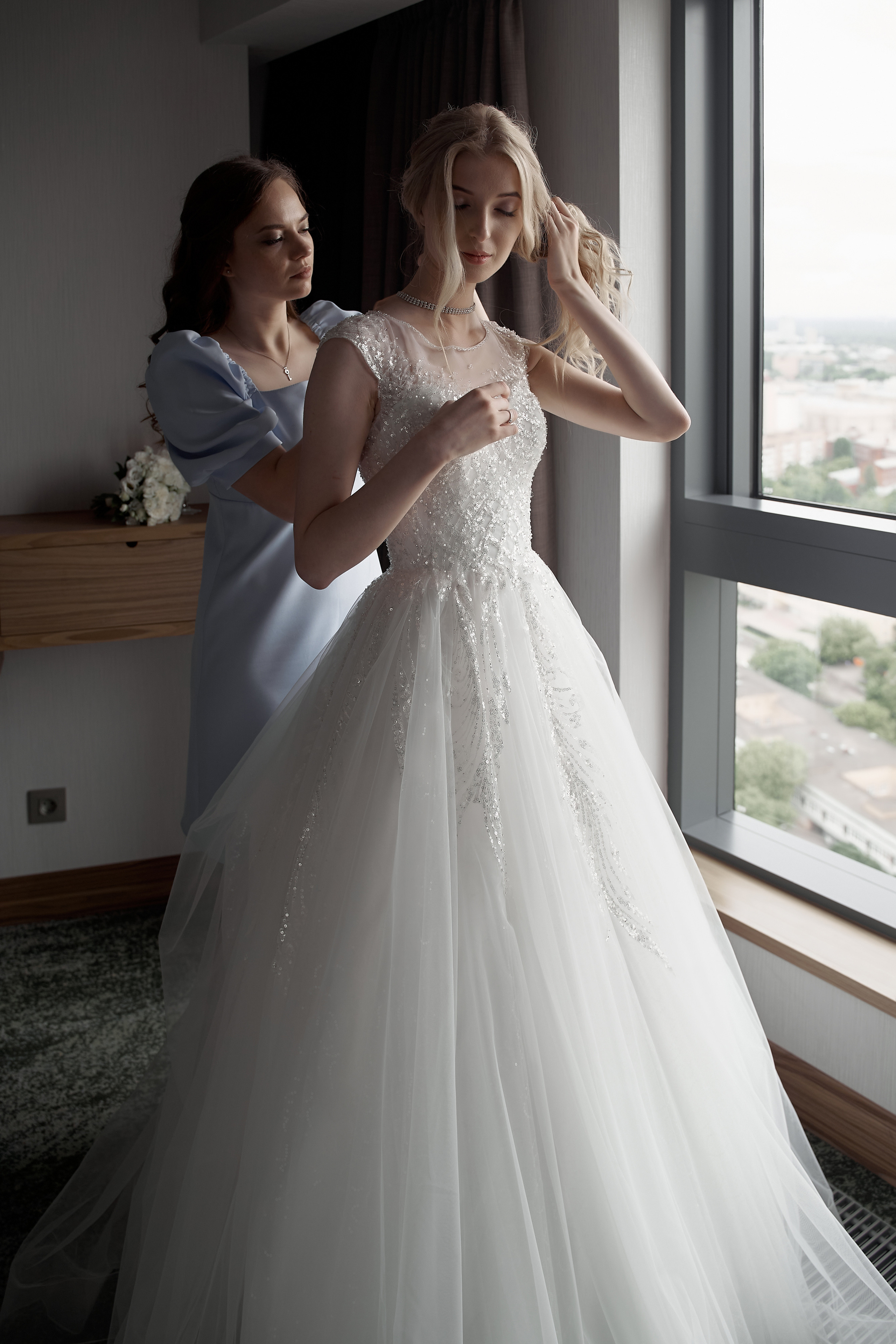 Сборы невесты утром у окна. подруга помогает собраться Свадебная фотосъемка в Москве. Свадебный фотограф в Москве  Сергей Гаварос.