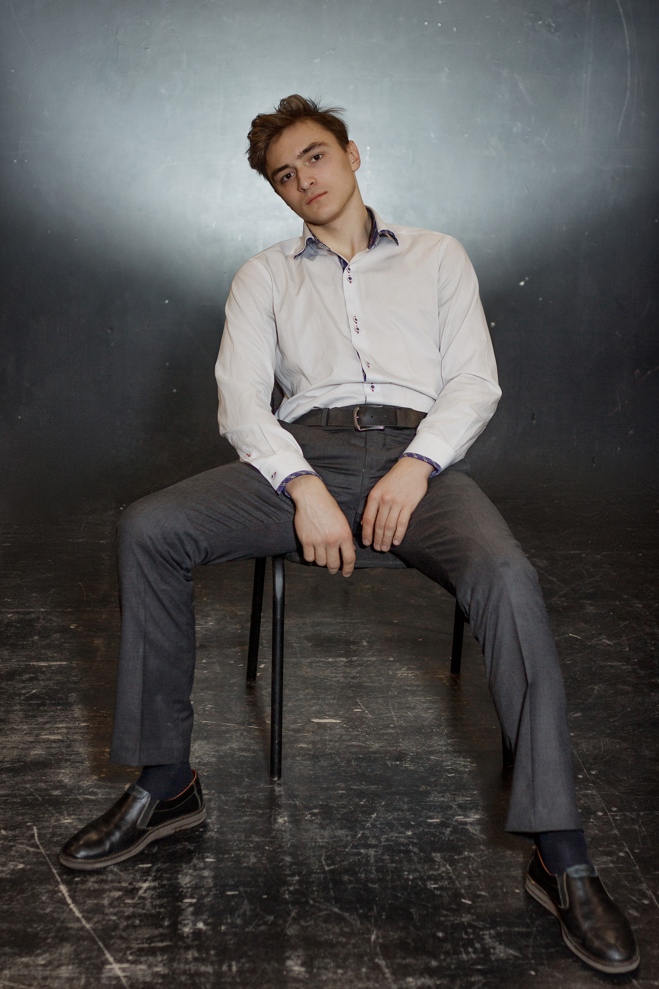 Юноша расслабленно сидит на стуле