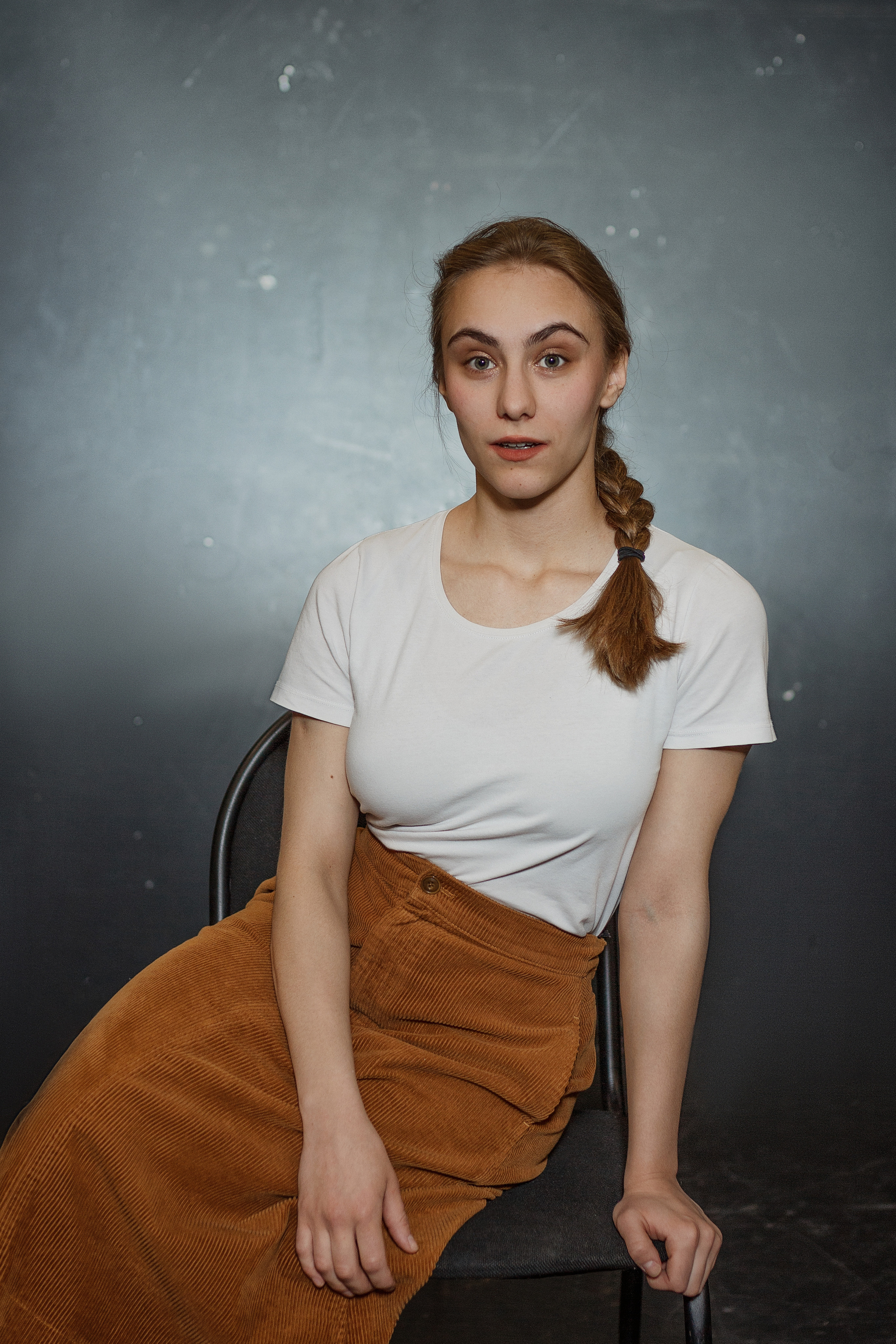 Портрет девушки в юбке сидит на стуле