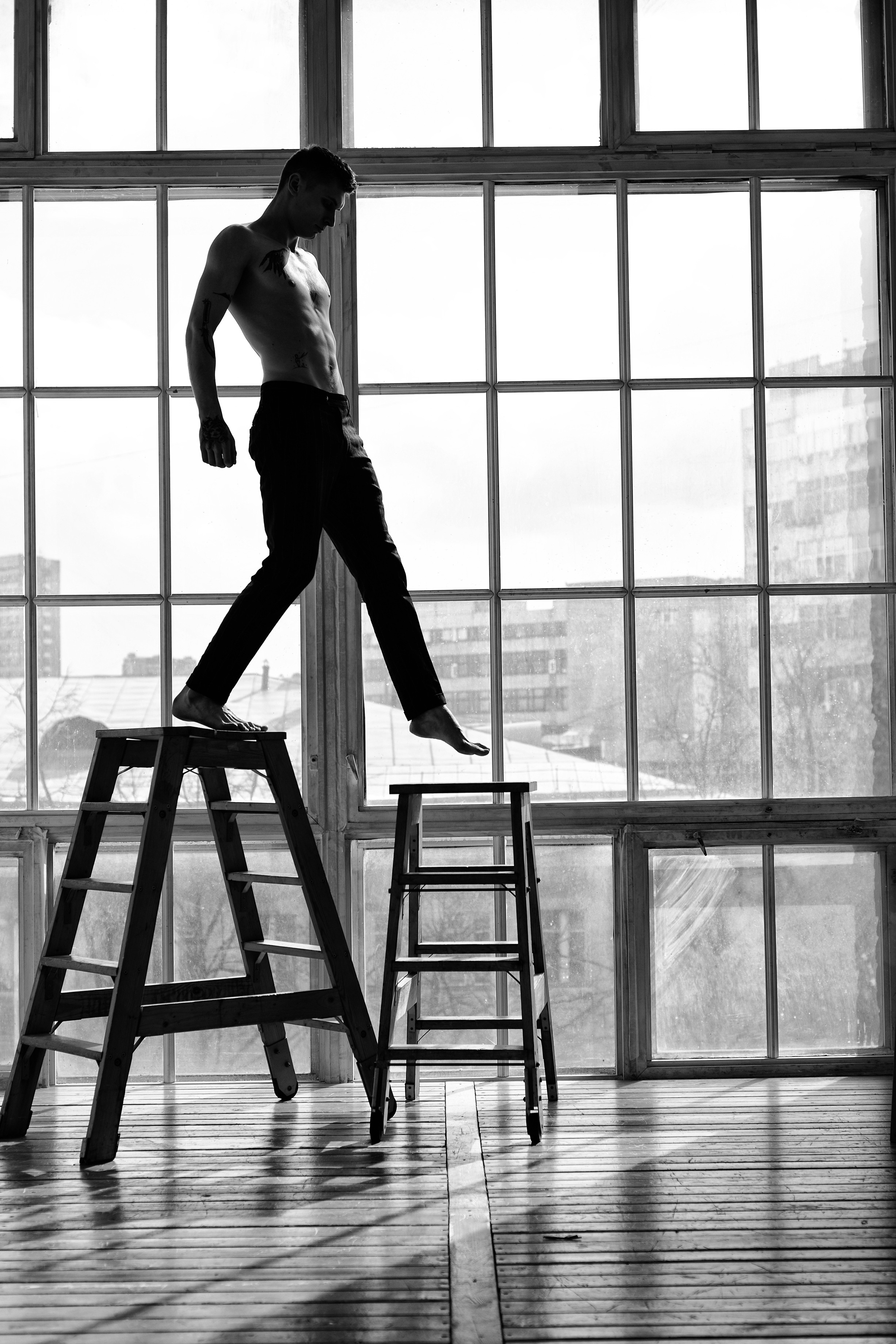 Мужчина в полосатых брюках на против окна идет по лестнице