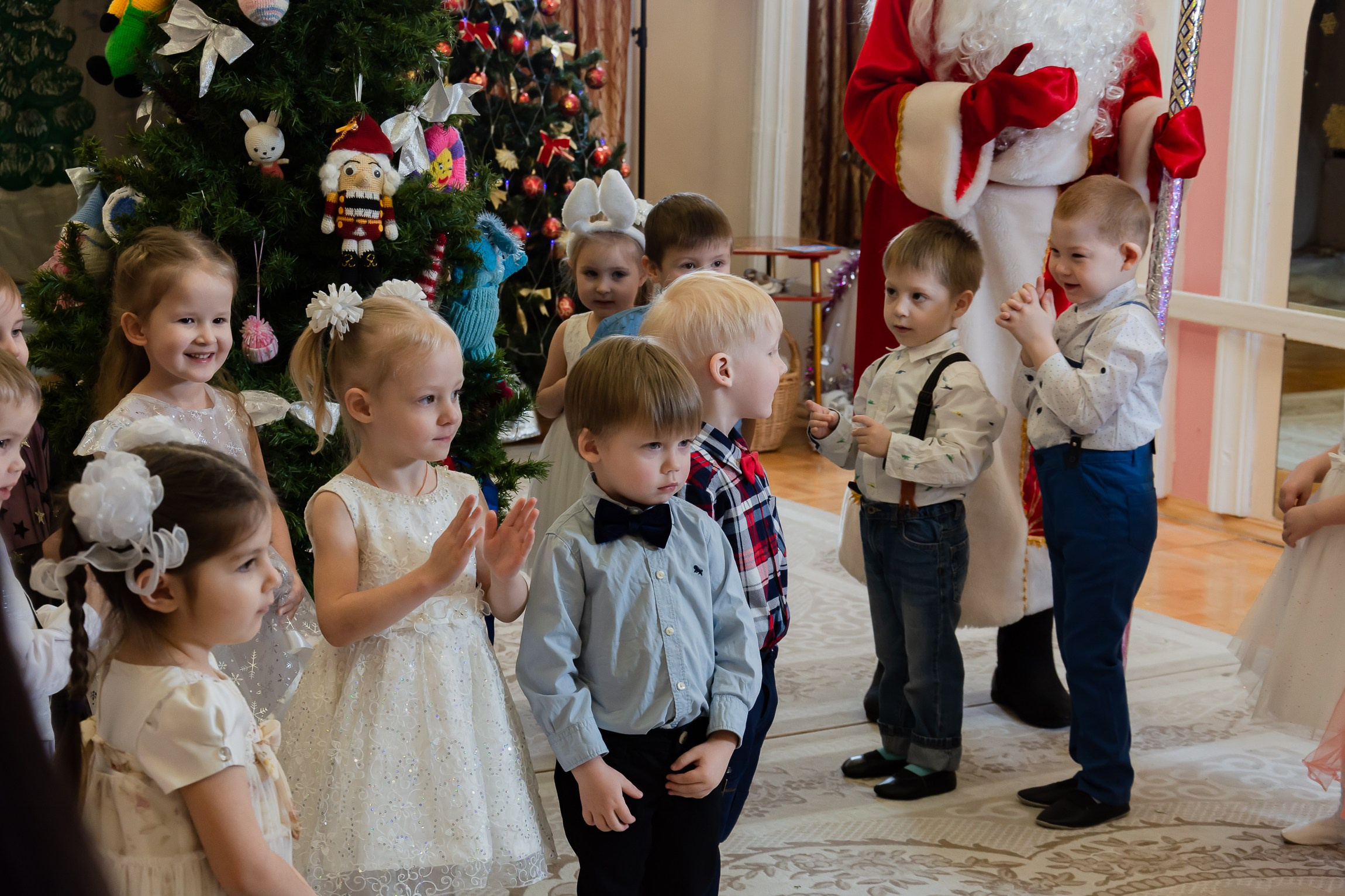 Дети пляшут рядом с новогодней елкой