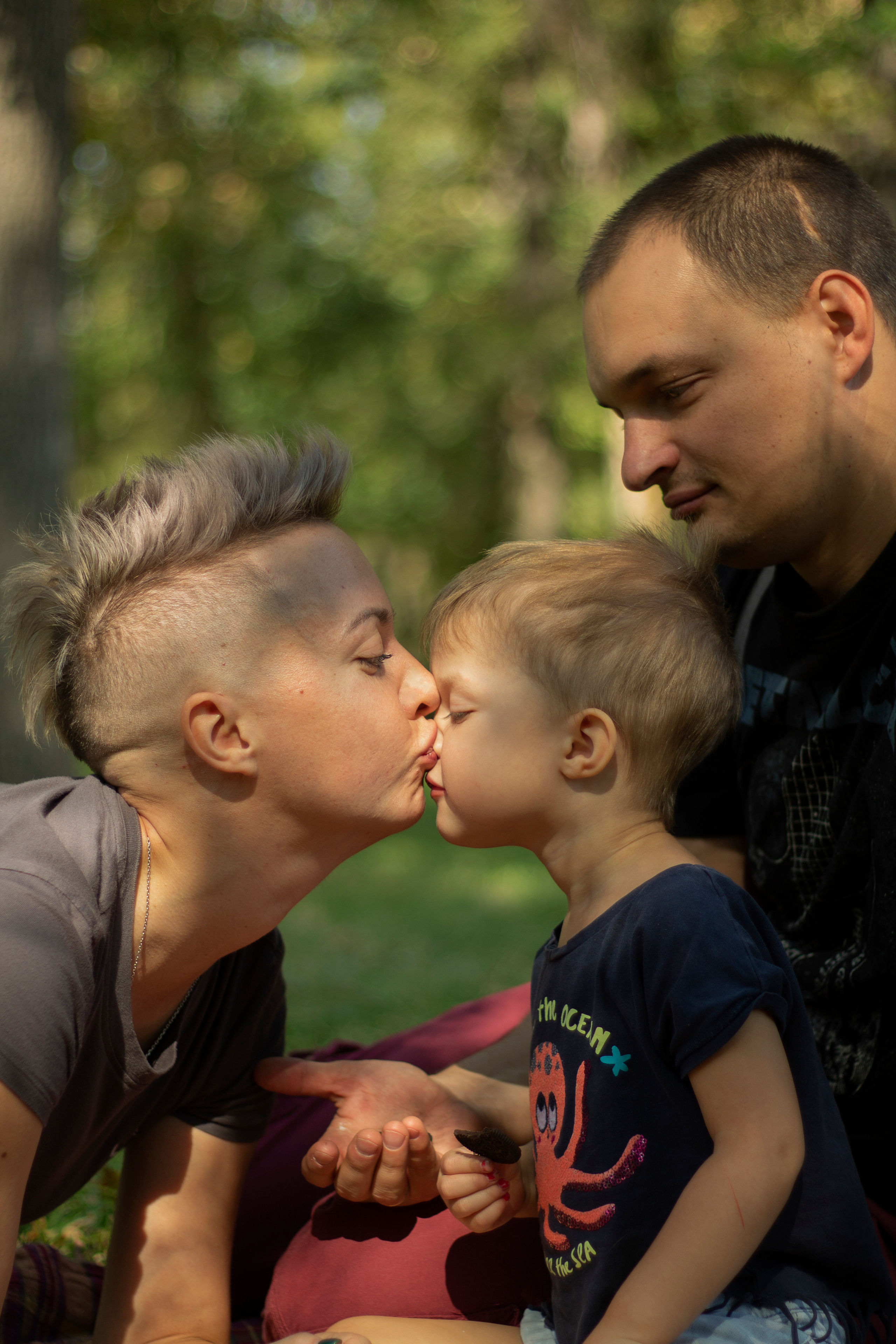 Папа держит дочь на руках а мама целуется с дочерью