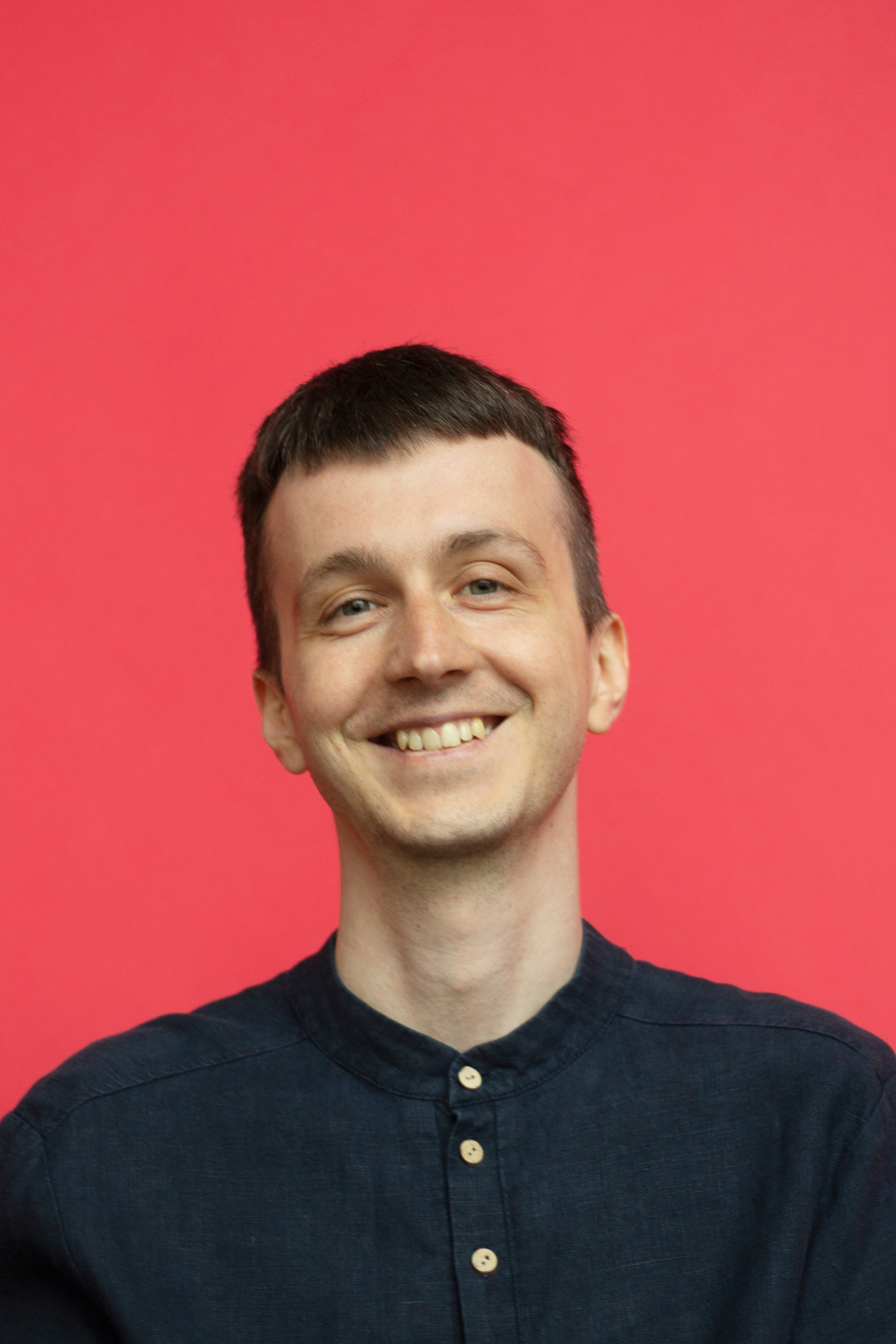 Мужчина в черной рубашке на красном фоне улыбается в камеру фото для Agenda 