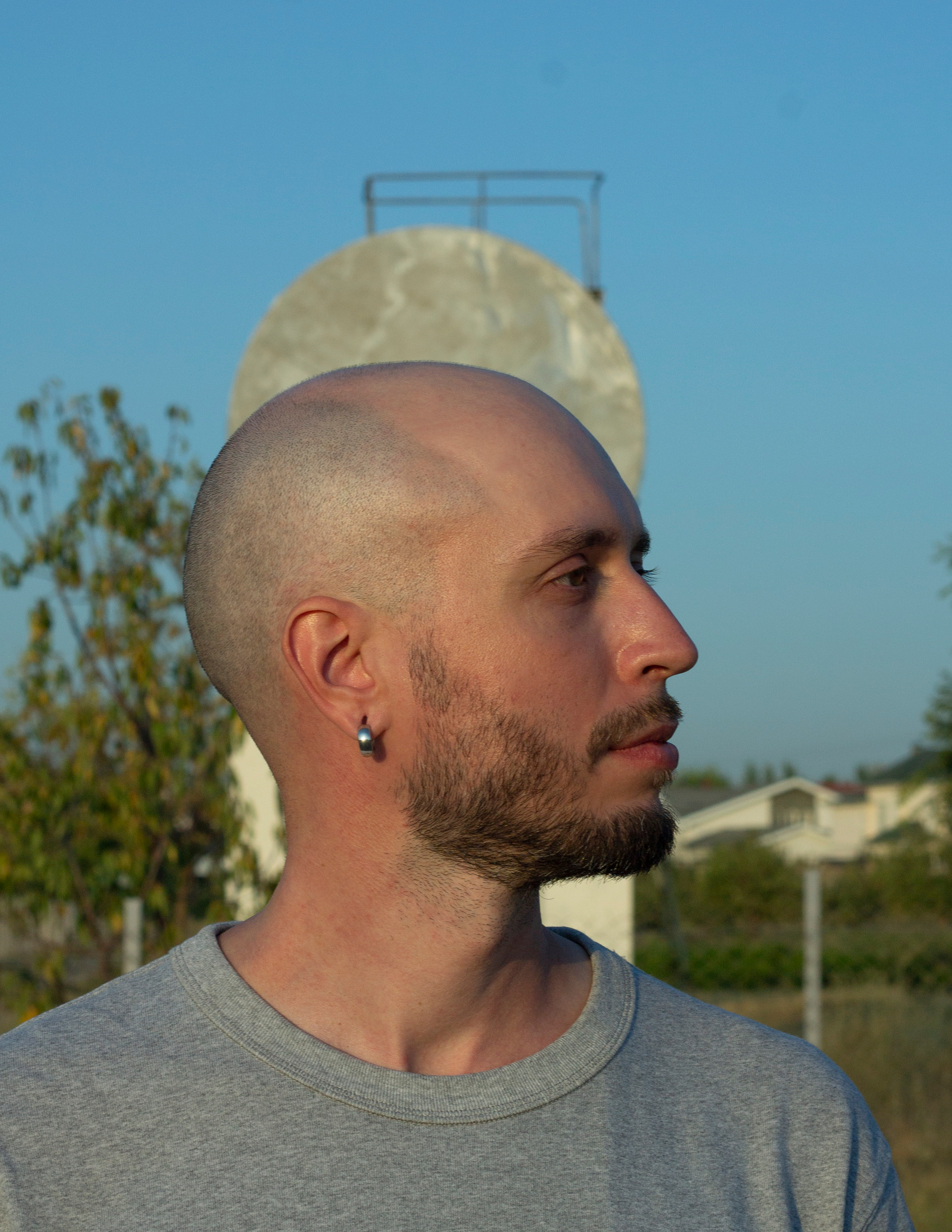 Профиль бритого мужчины с нимбом из бочки на фоне неба