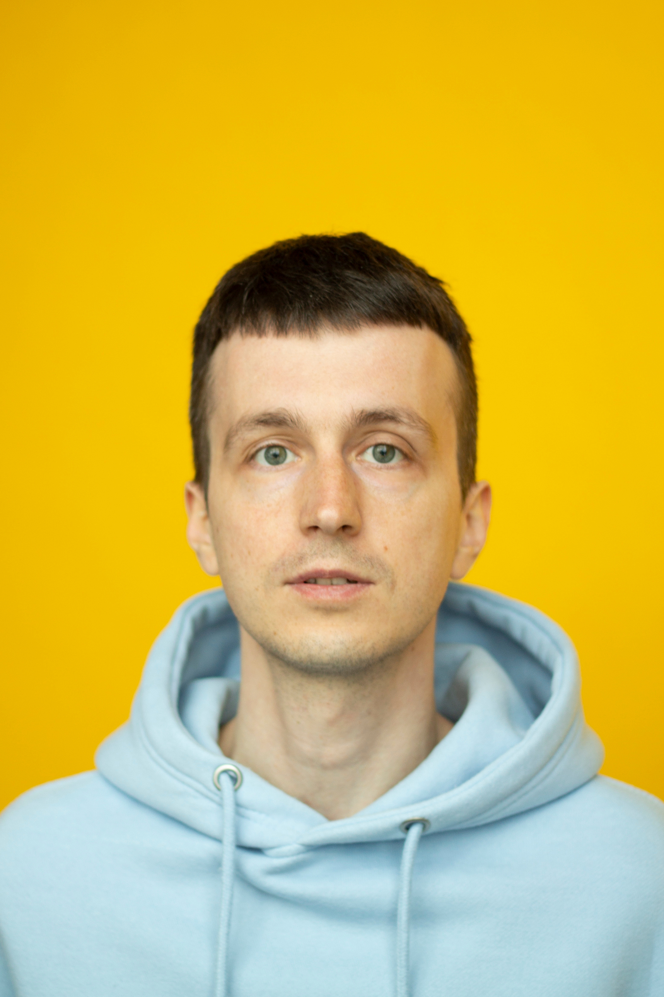 Портрет мужчины в голубой толстовке на желтом фоне фотограф Анна Карамузина