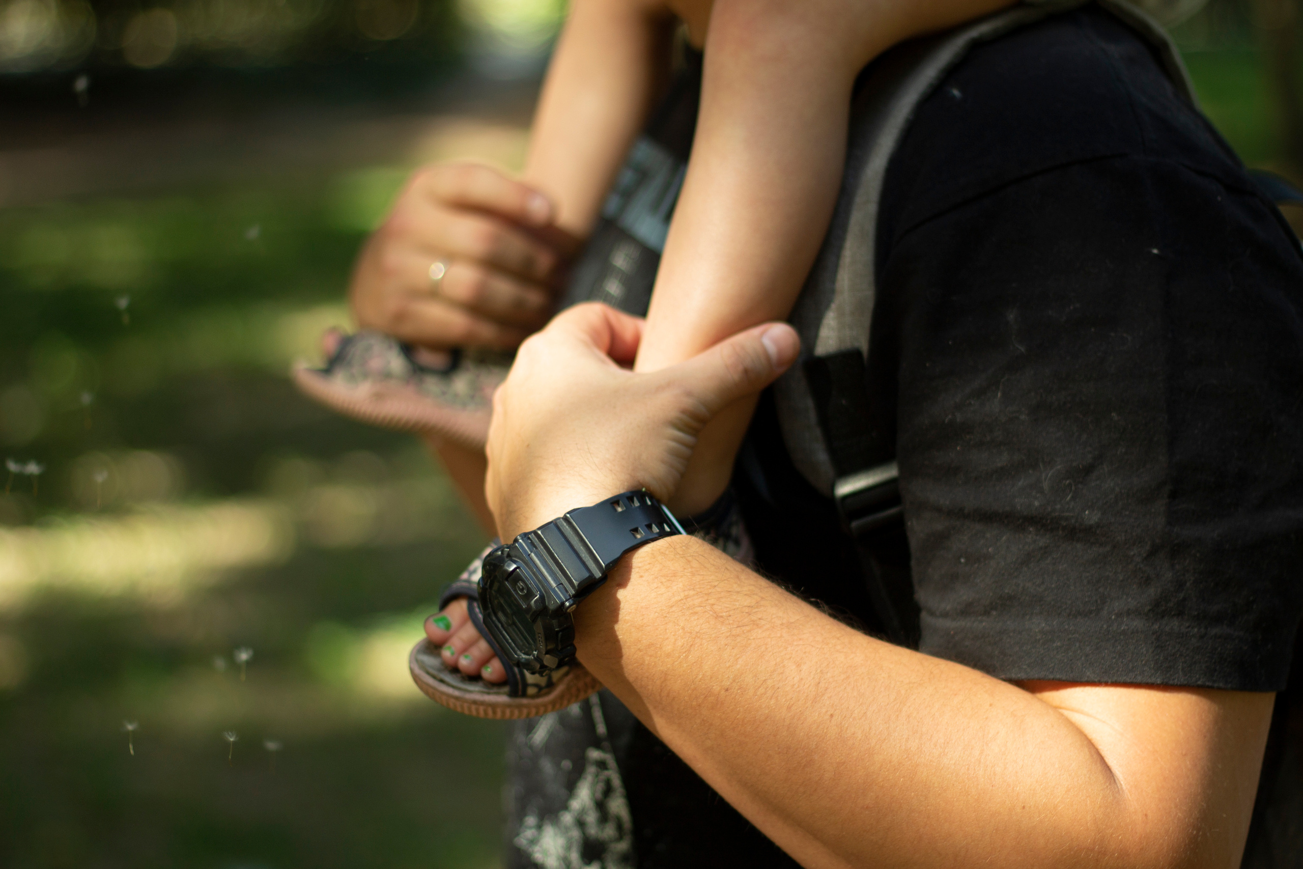 Папины руки держат ноги дочери которая сидит у него на плечах