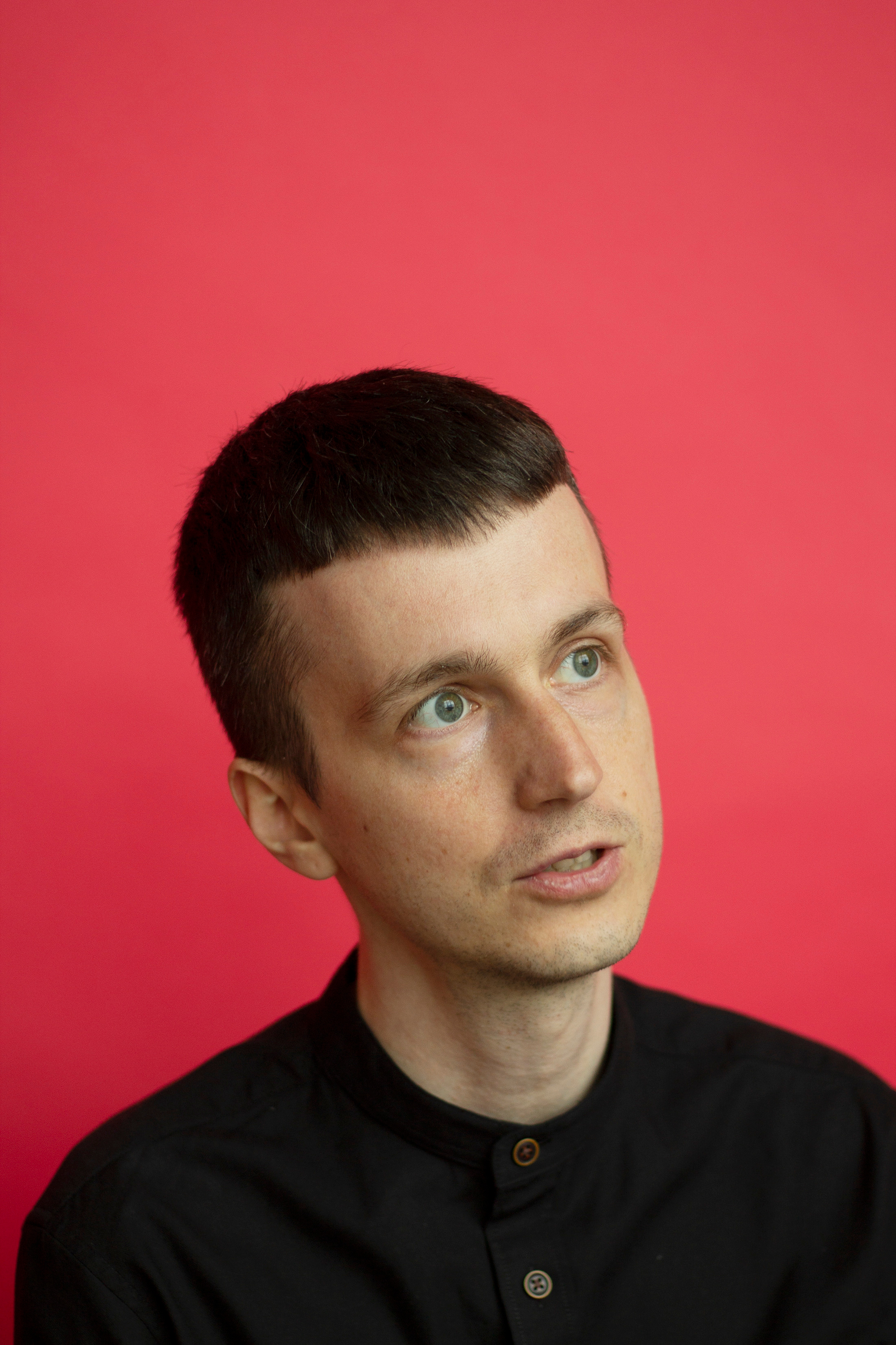 Парень в черной рубашке говорит на красном фоне фотограф Анна Карамурзина