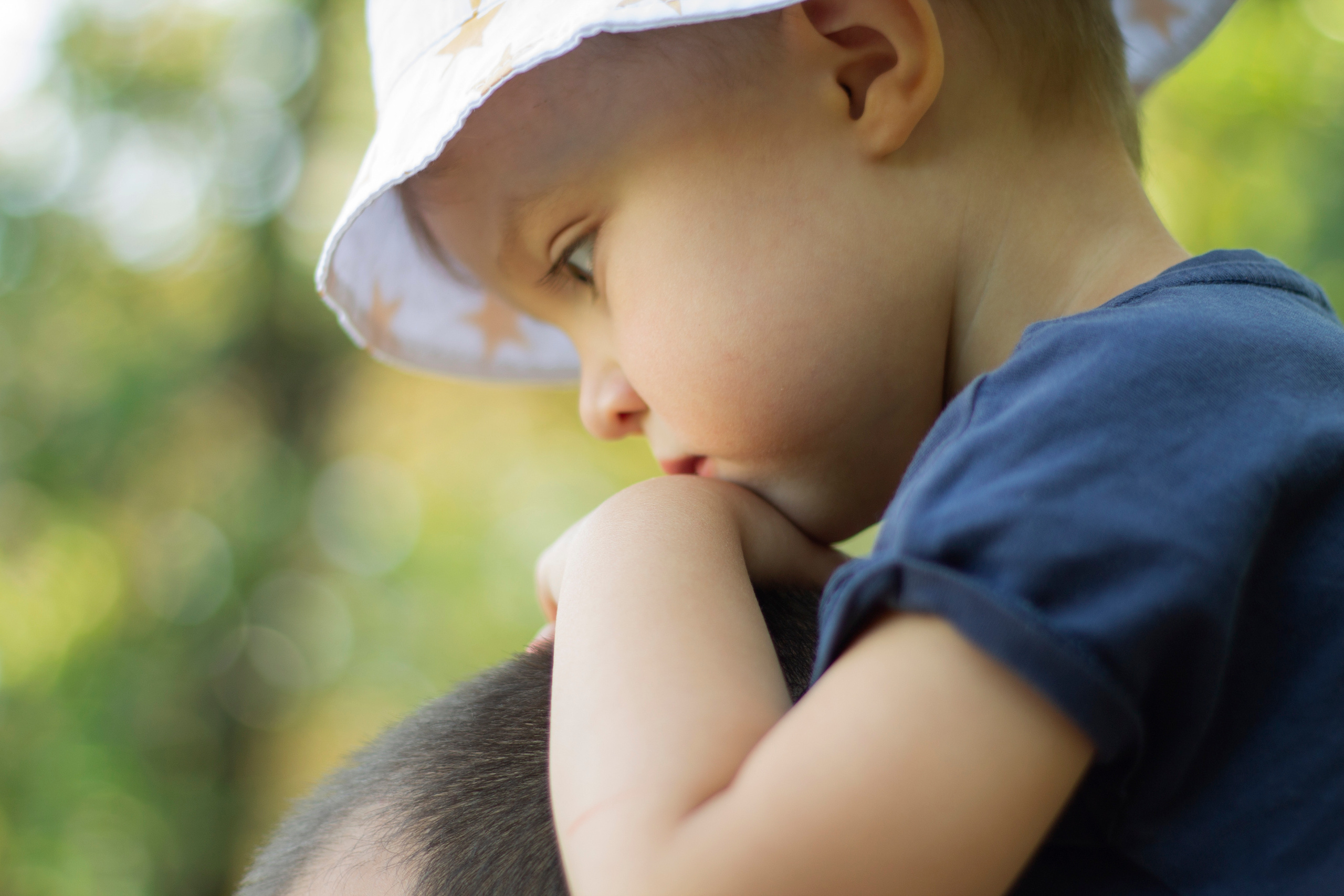 Дочь в панаме на плечах у папы сложила руки ему на голову а сверху положила свой подбородок
