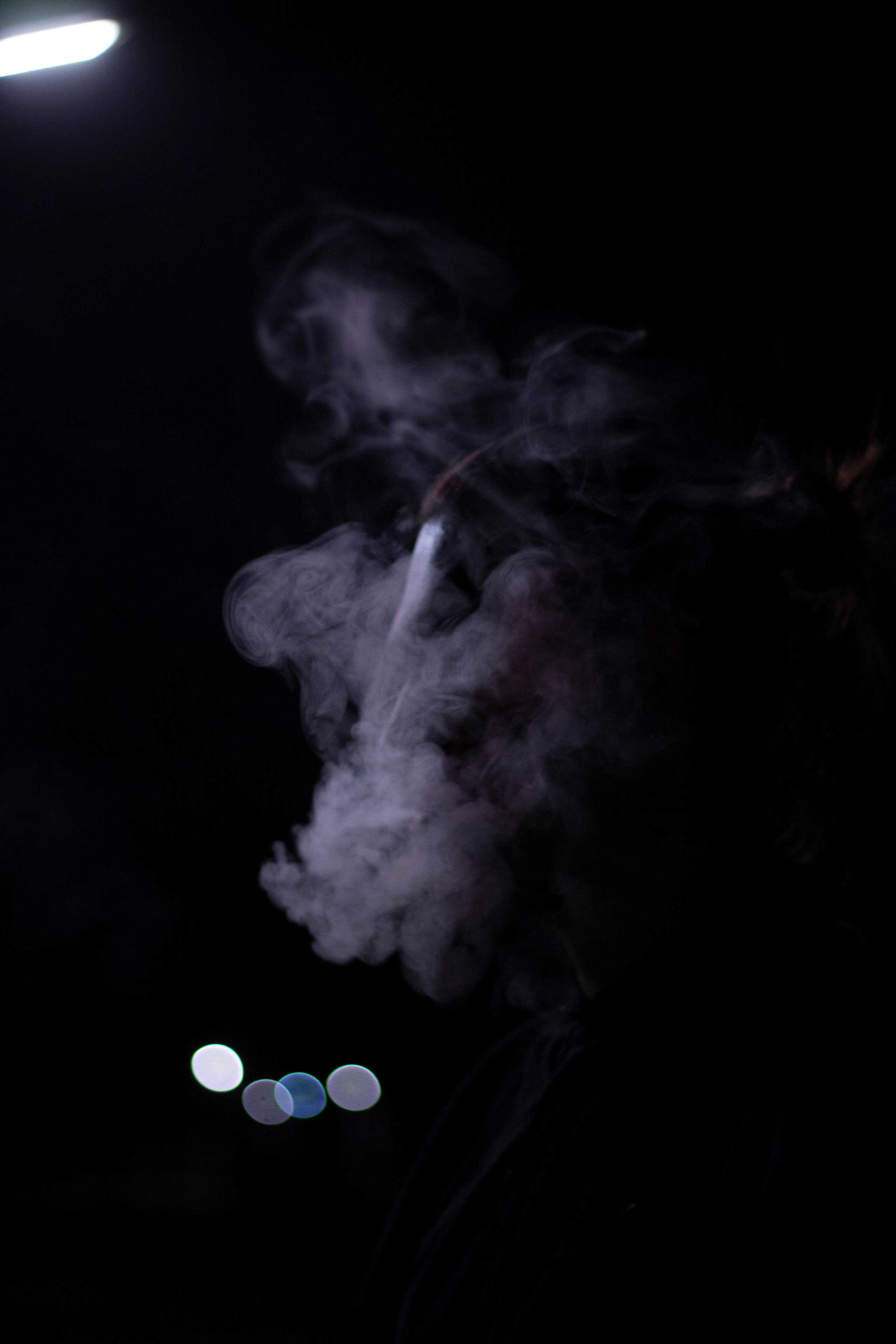 Фиолетовый дым сигарет закрывает лицо мужчины в ночном городе