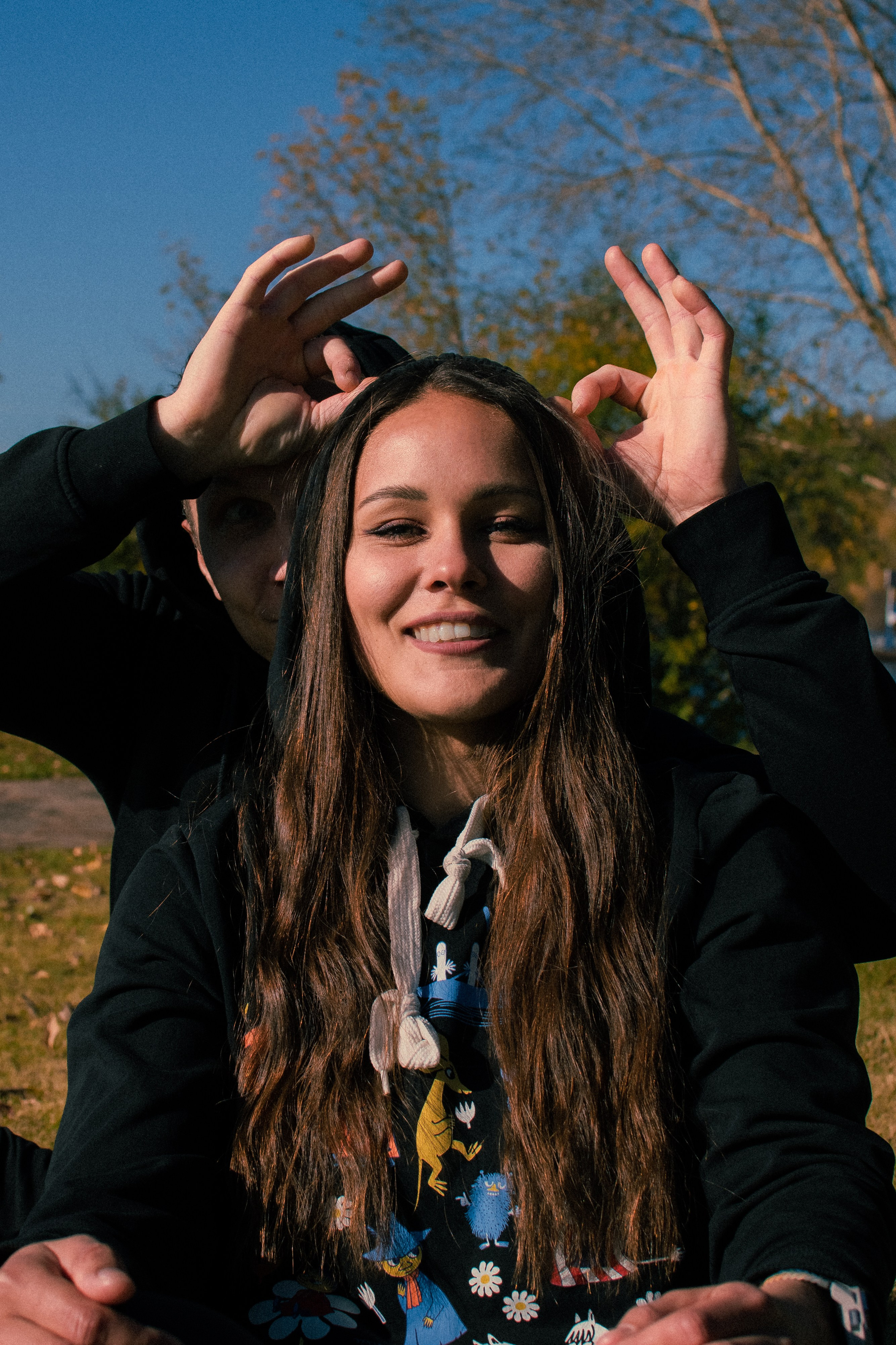 Парень подставил рожки девушке на фоне осеннего пейзажа