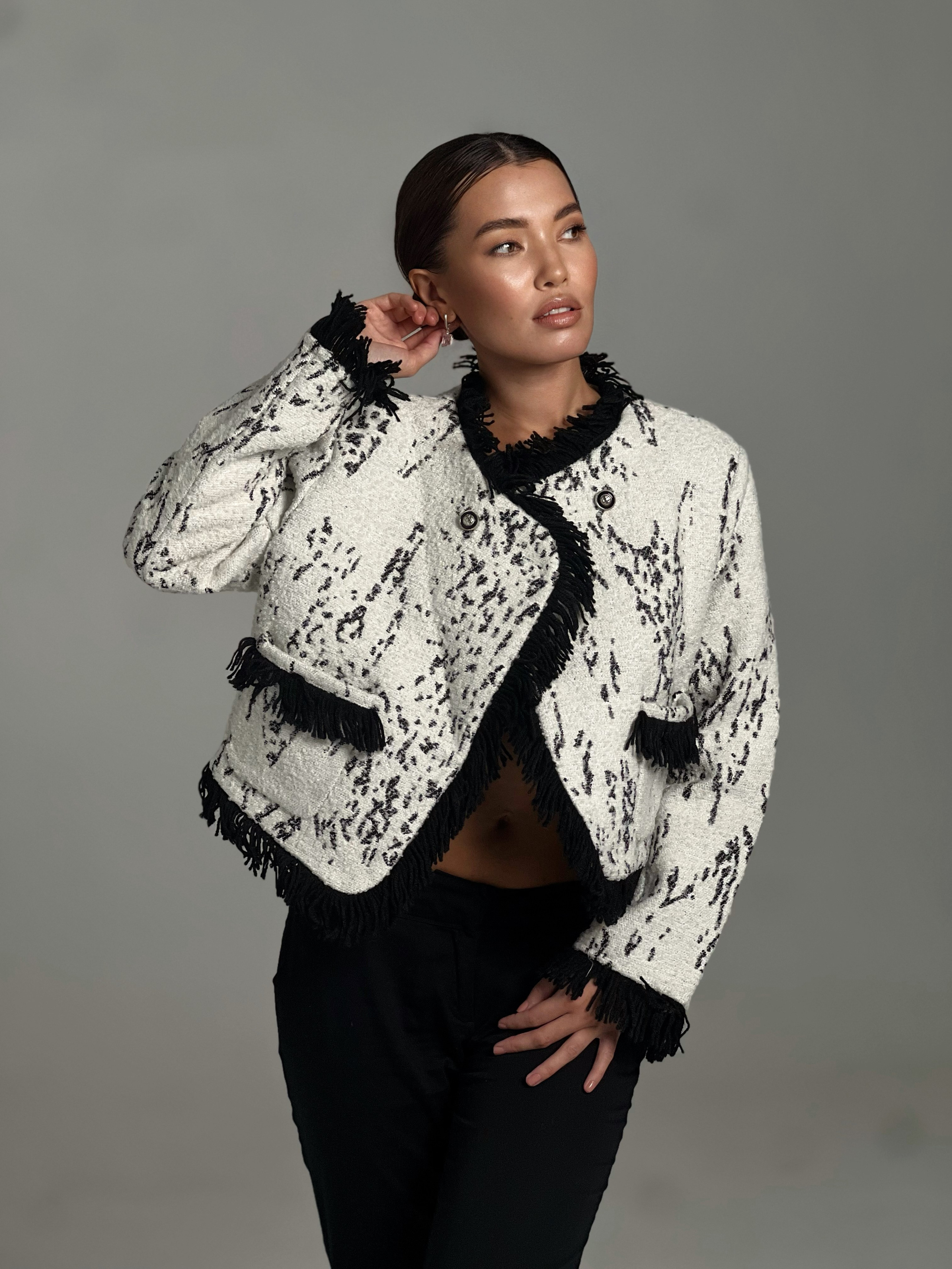 Девушка азиатской внешности позирует в светлом жакете на сером фоне