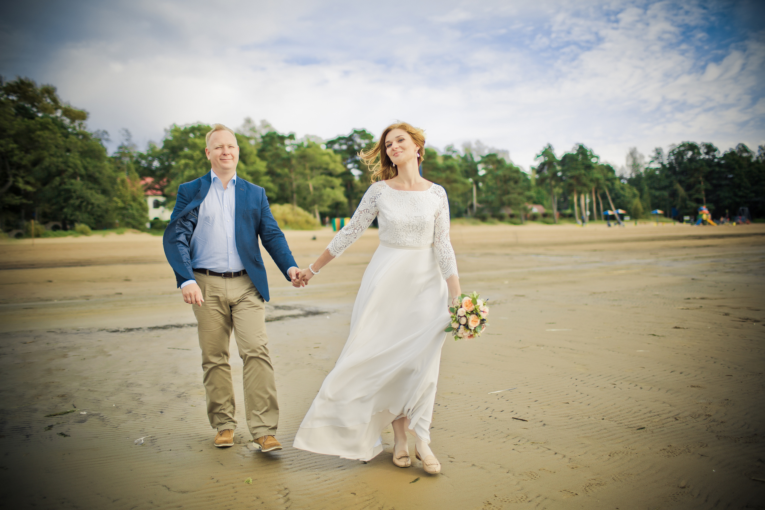 невеста ведет суженого за руку по пляжу