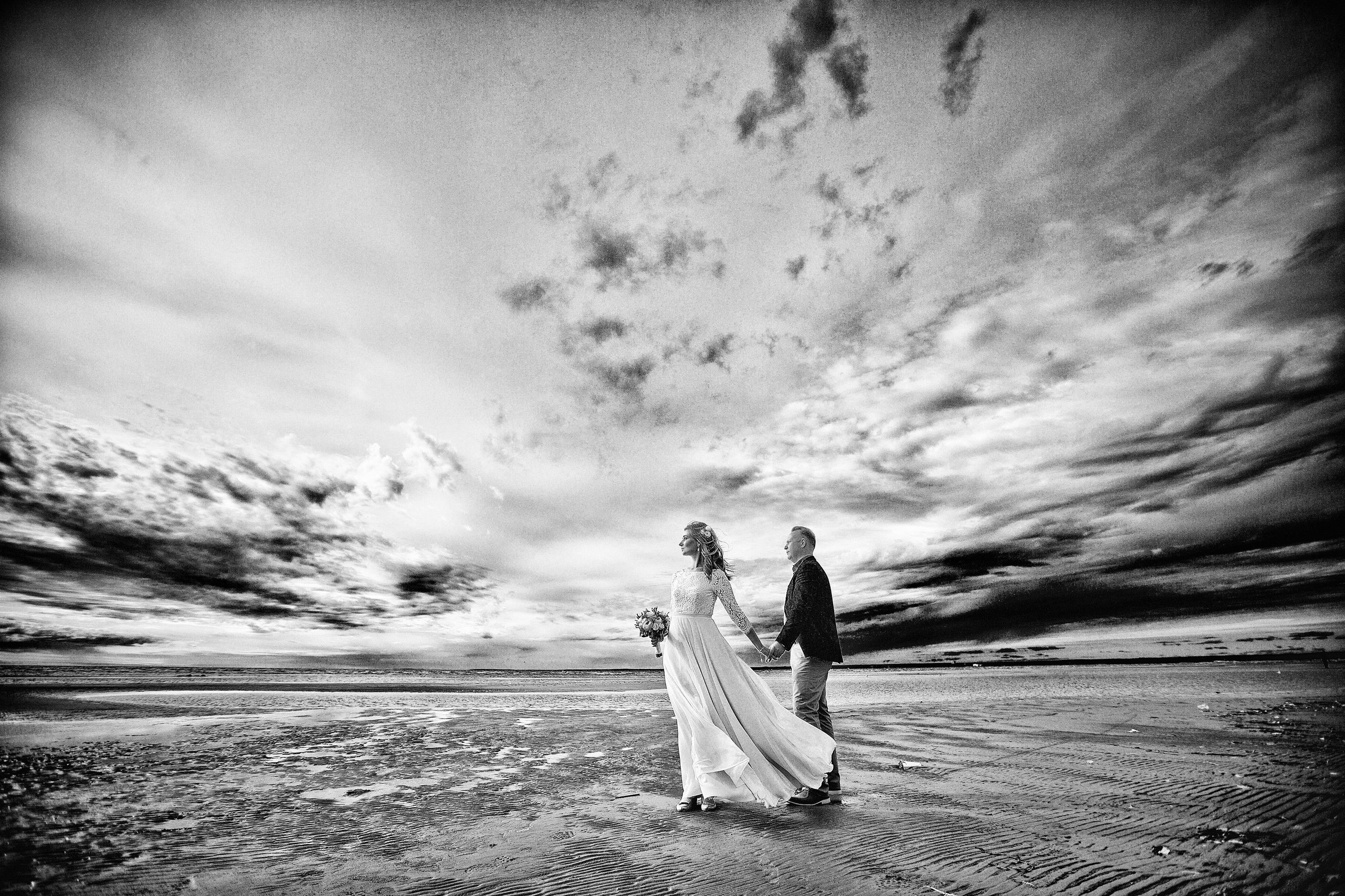 жених и невеста на фоне пляжа финского залива уходящих вдаль облаков