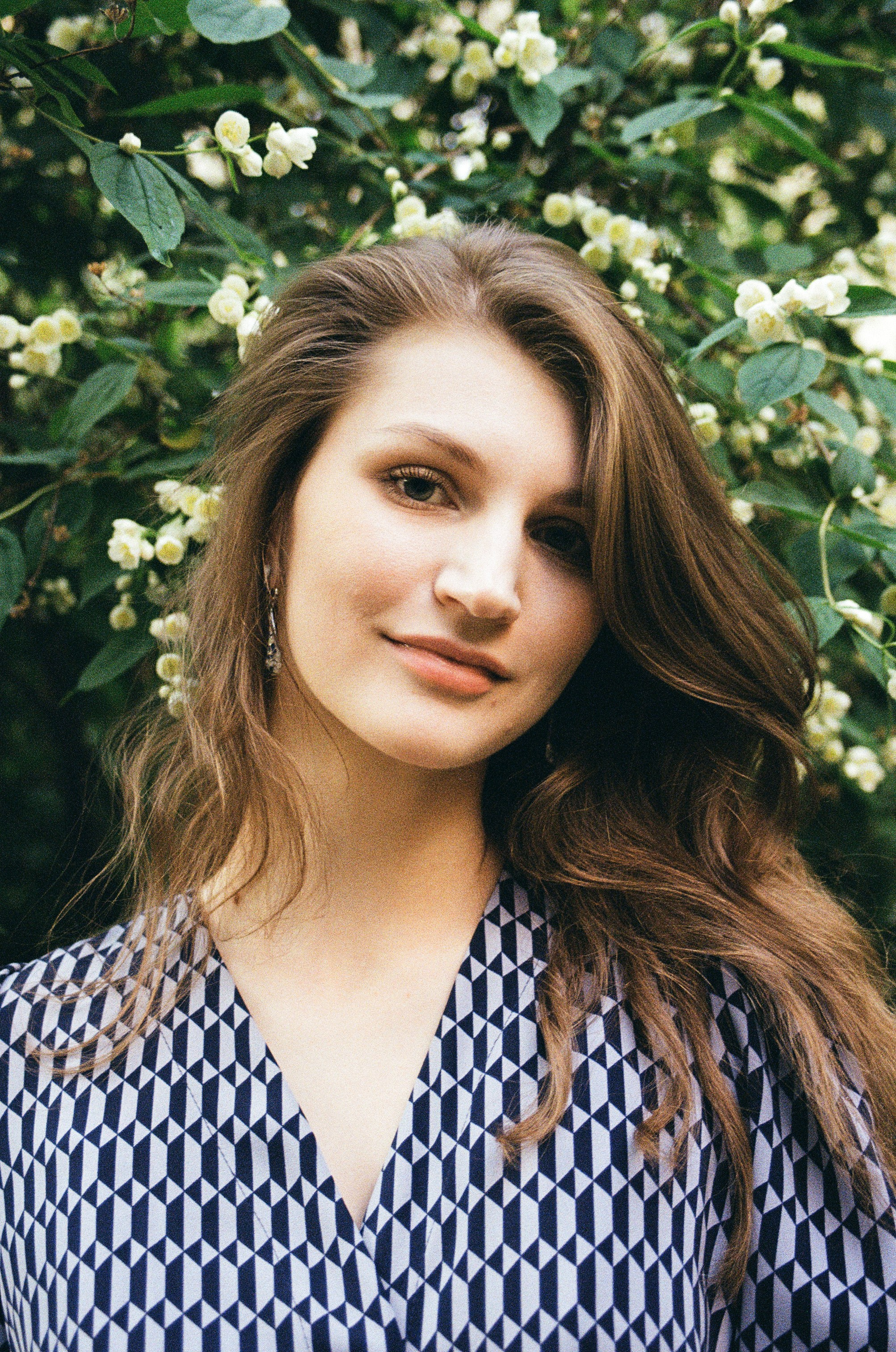 Портрет красивой девушки на фоне цветущего садового жасмина