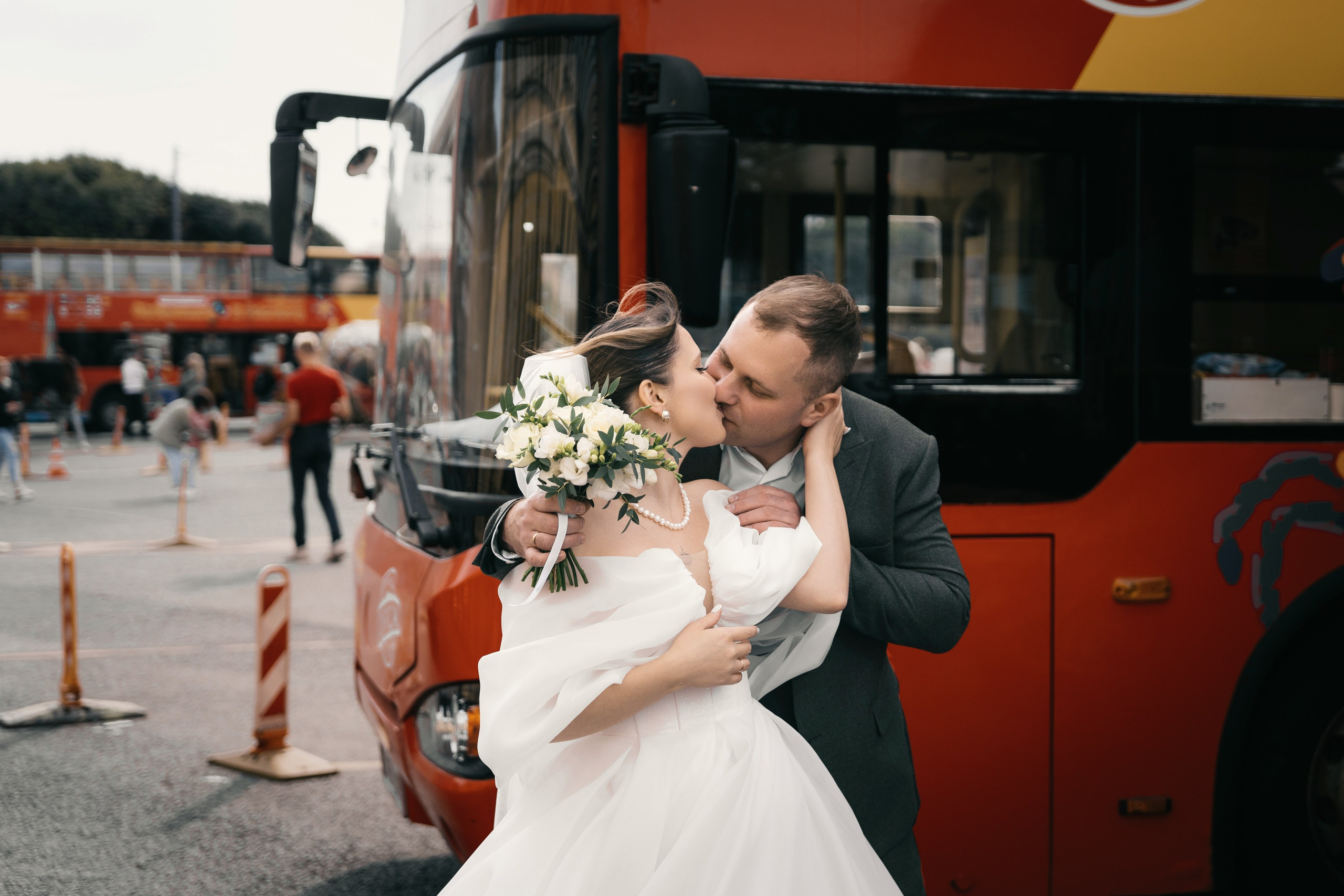 жених и невеста у красных туристических автобусов у Исаакиевского собора на свадебной фотосессии
