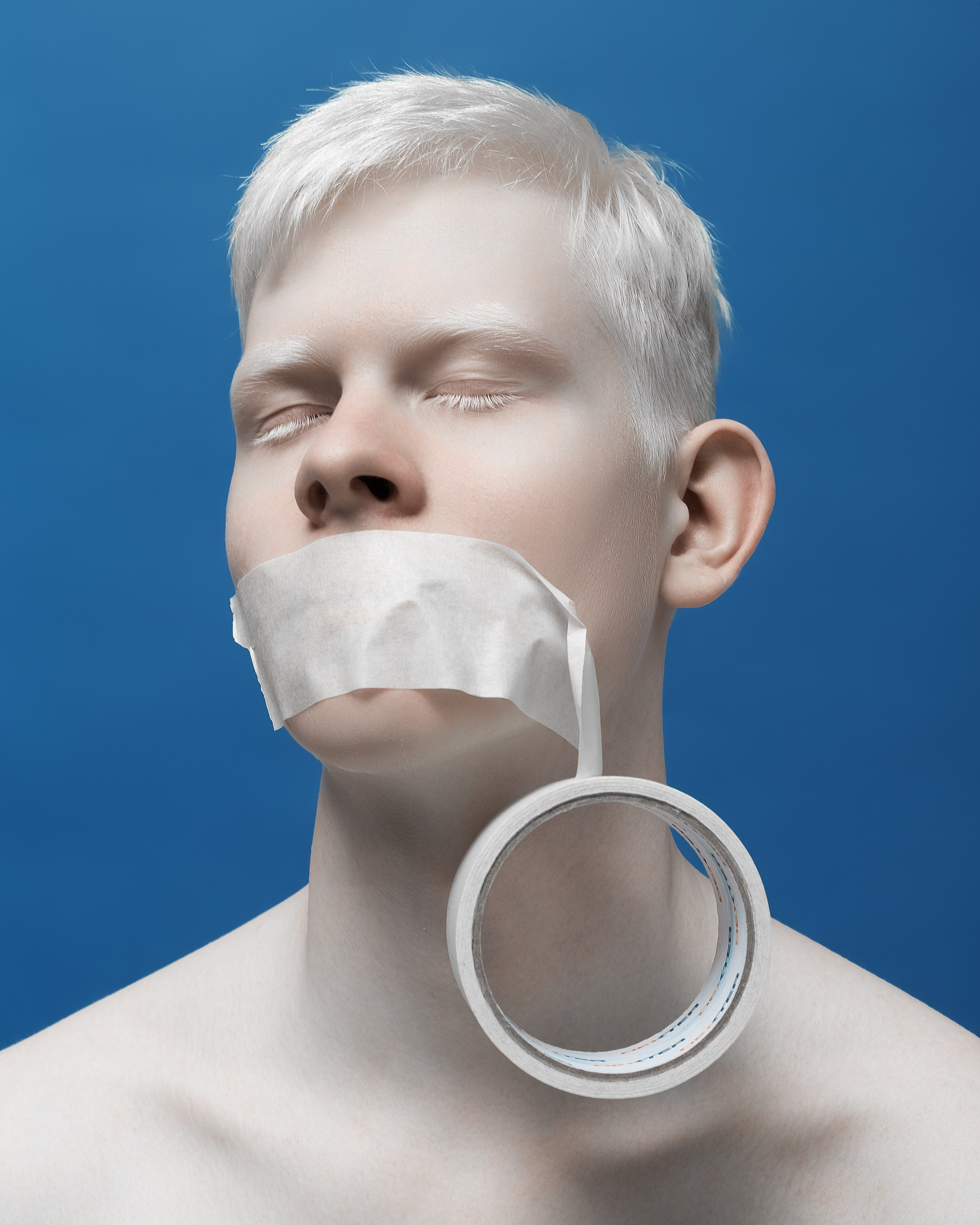 Парень альбинос с заклеенным ртом скотчем на синем фоне, творчество с альбиносом Казань