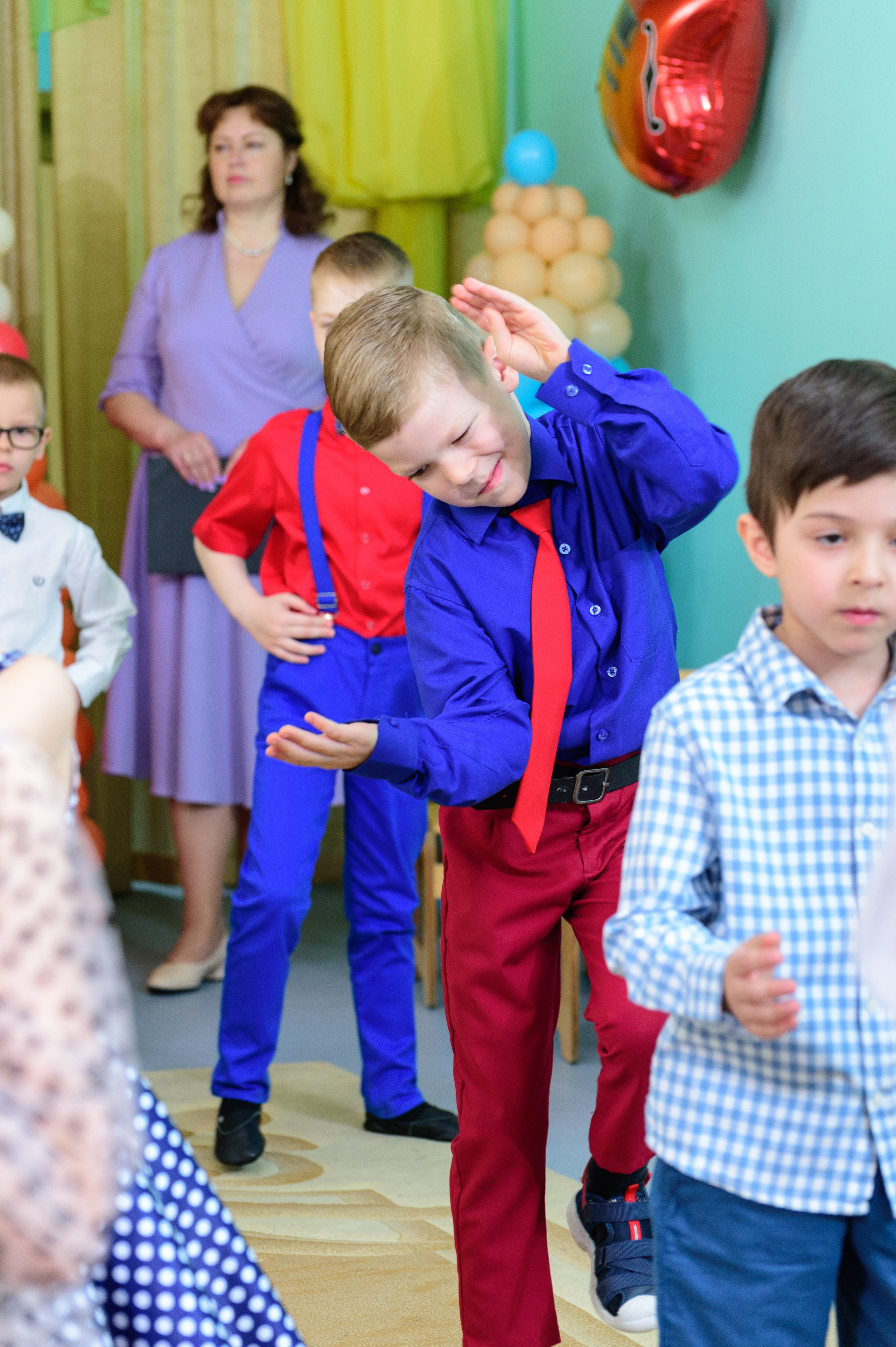 Мальчик танцует на утреннике в детском саду.