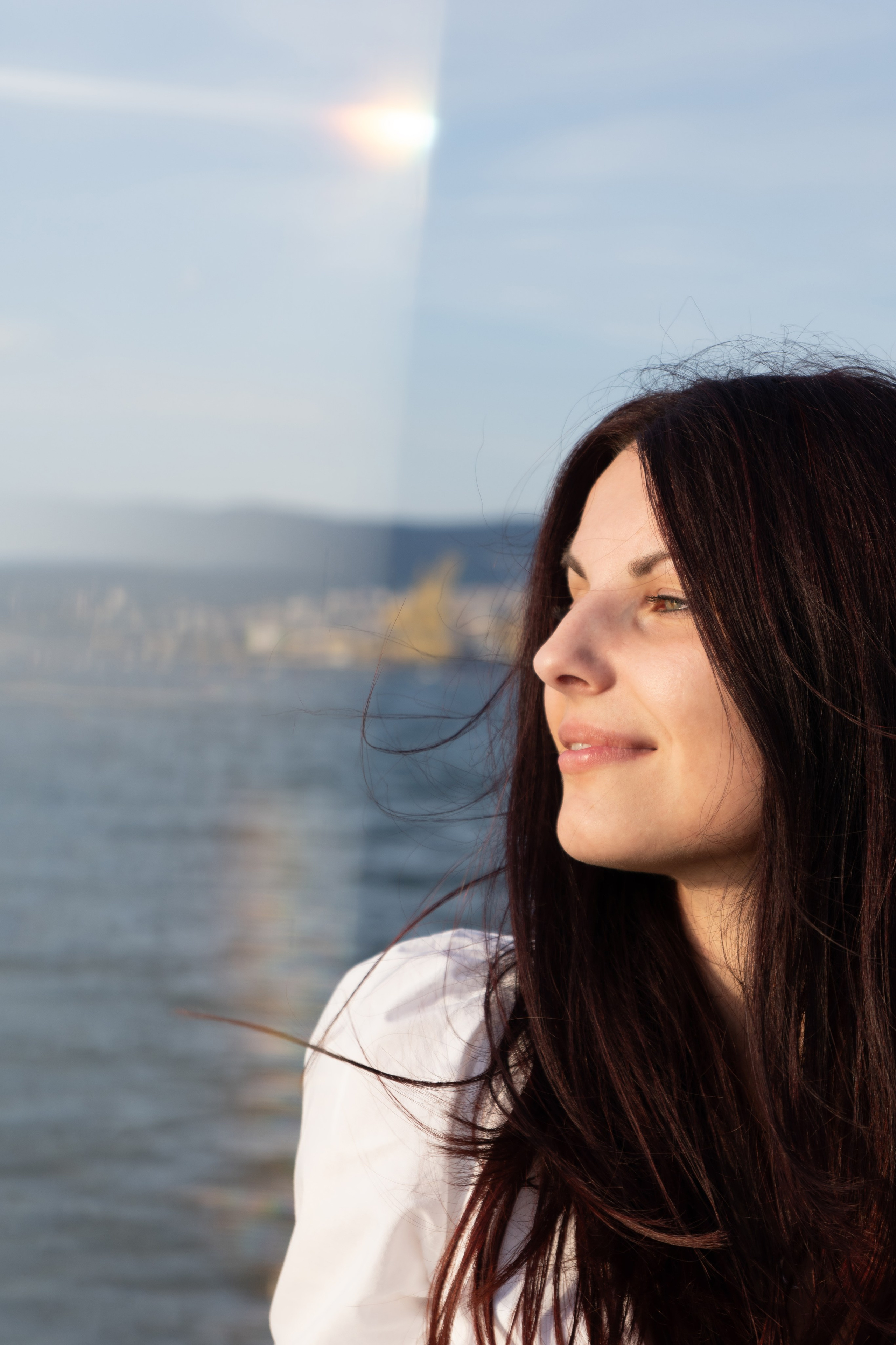 Ritratto di donna, in riva al mare sotto la luce naturale con riflessi del sole