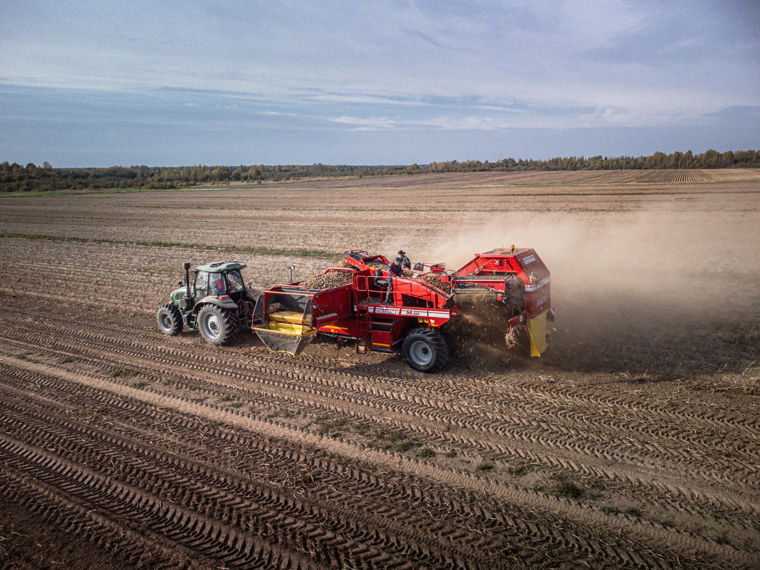 трактор со специальным прицепом собирает готовый урожай картофеля с поля, сельское хозяйство Любимского района, Ярославской области, спецтехника, поле, песок, пыль