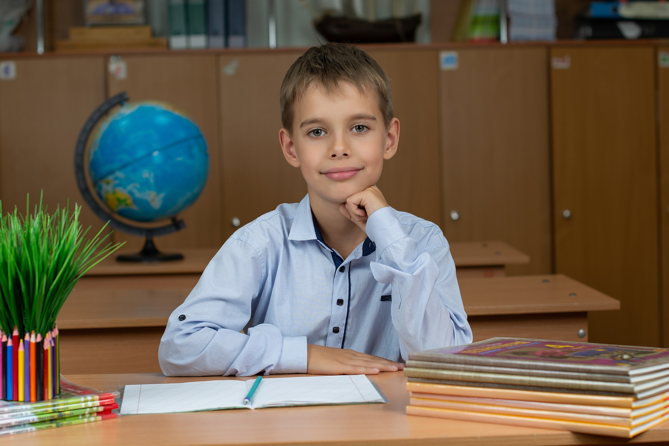 Милый парень в голубой рубашке на фотосессии в классе.