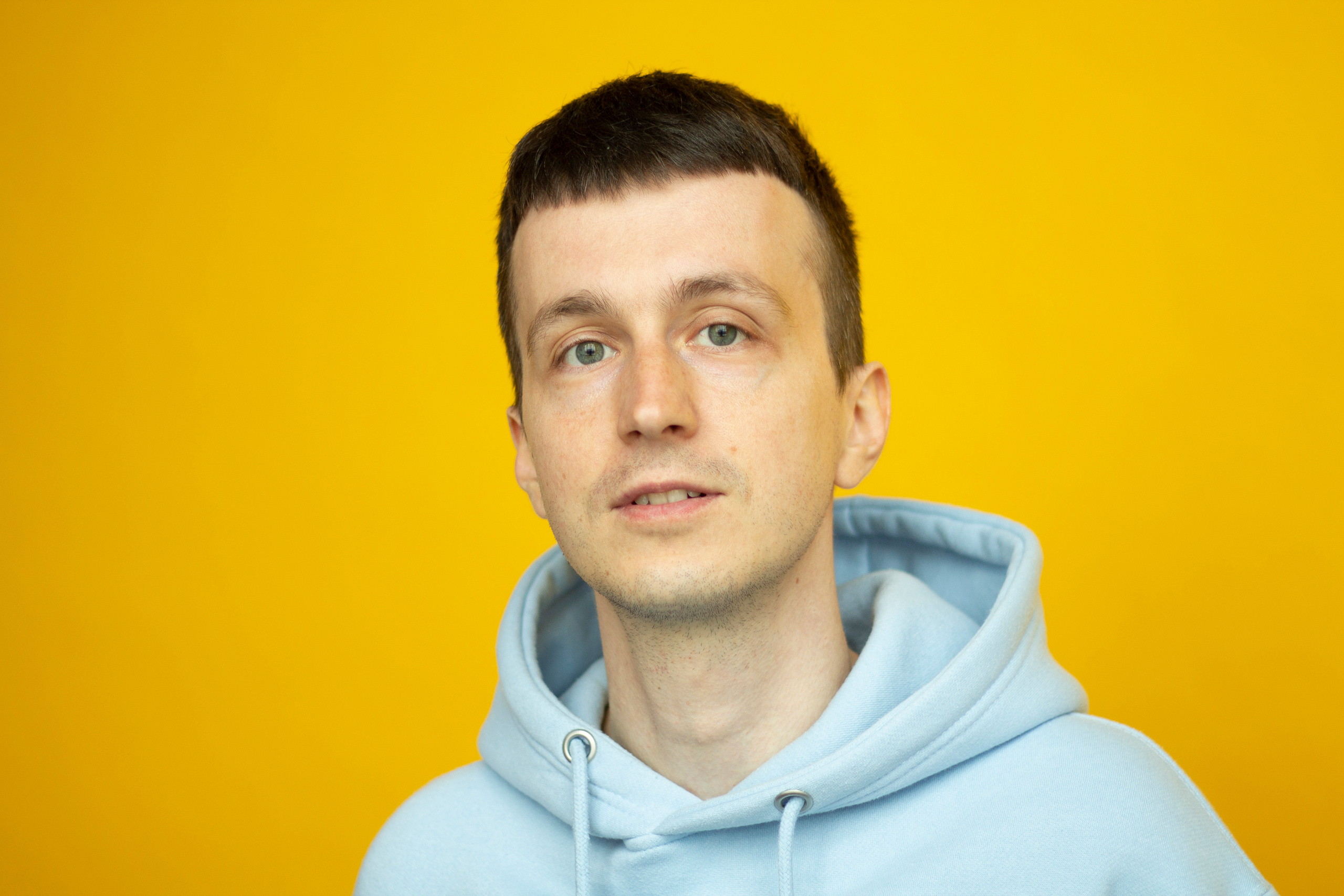 Man portrait in blue hoodie  on the yellow background