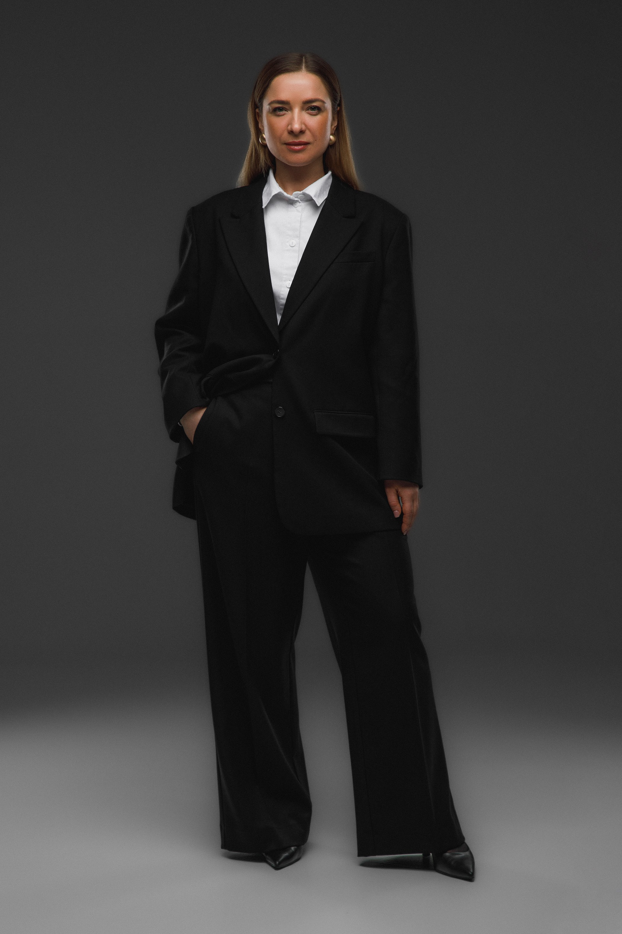 Фотография женщины в студии в классическом черном деловом костюме.