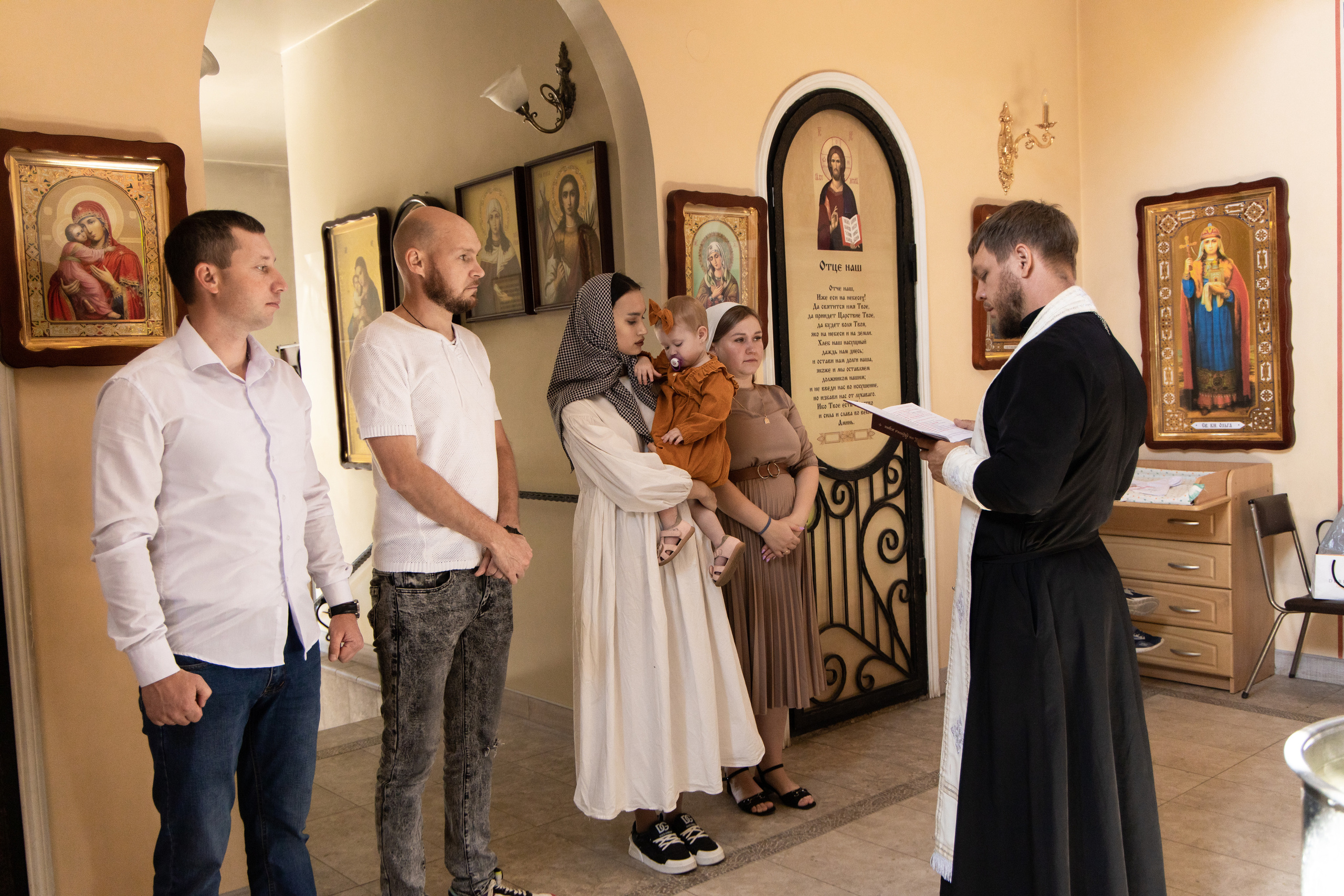 Прихожане с ребёнком на руках в церкви. Батюшка читает молитву. Крещение фотосессия  Астрахань.