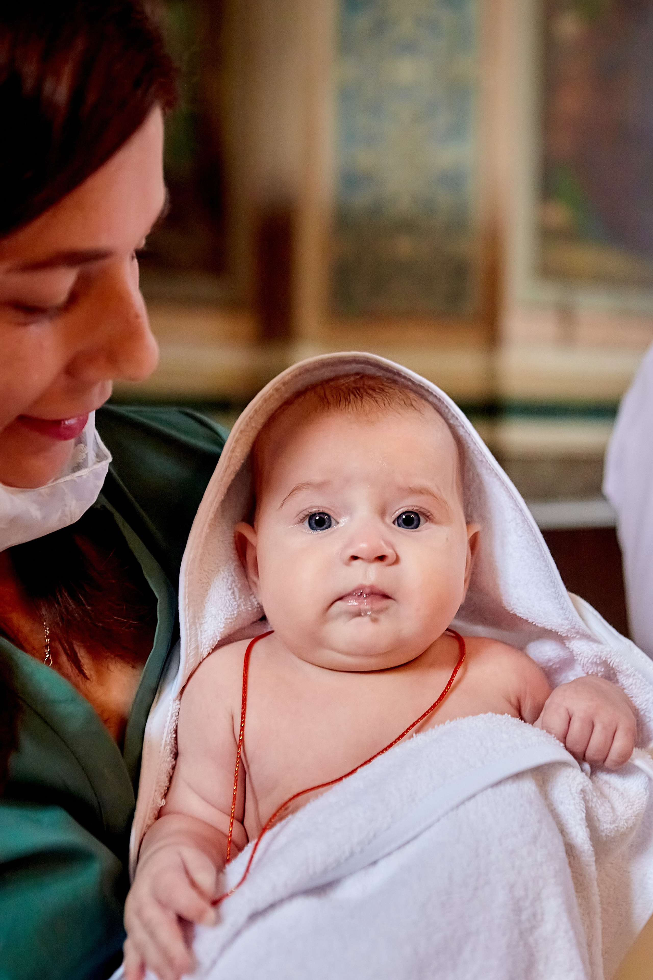 Малышка в объятиях мамы после купели