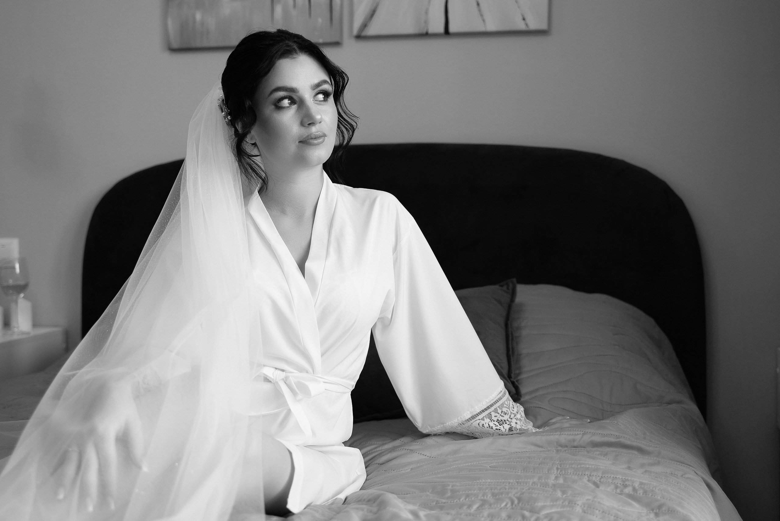 Невеста сидит на кровати в халате.